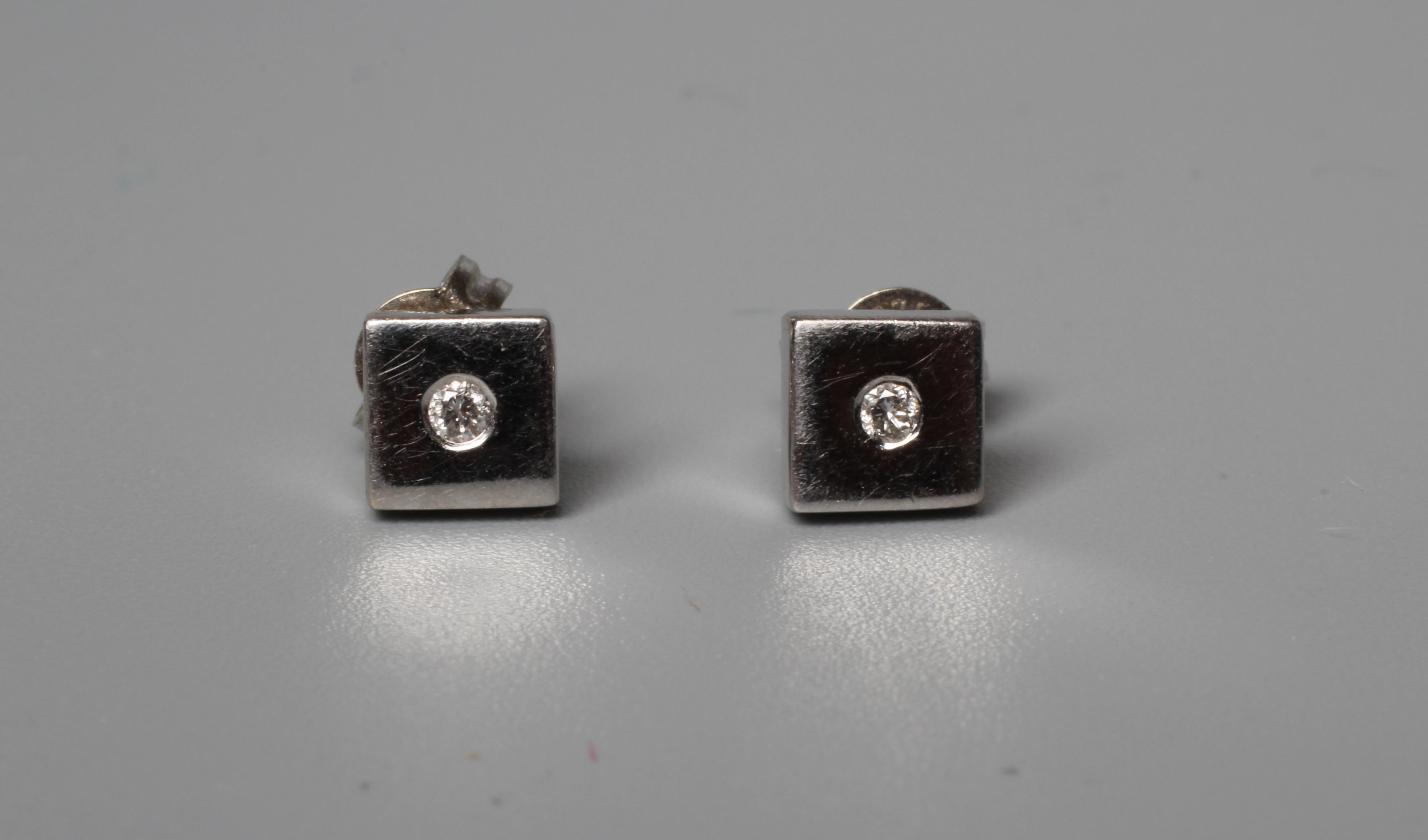 A PAIR OF DIAMOND EAR STUDS, the plain white square panels each set with a small round brilliant to Image