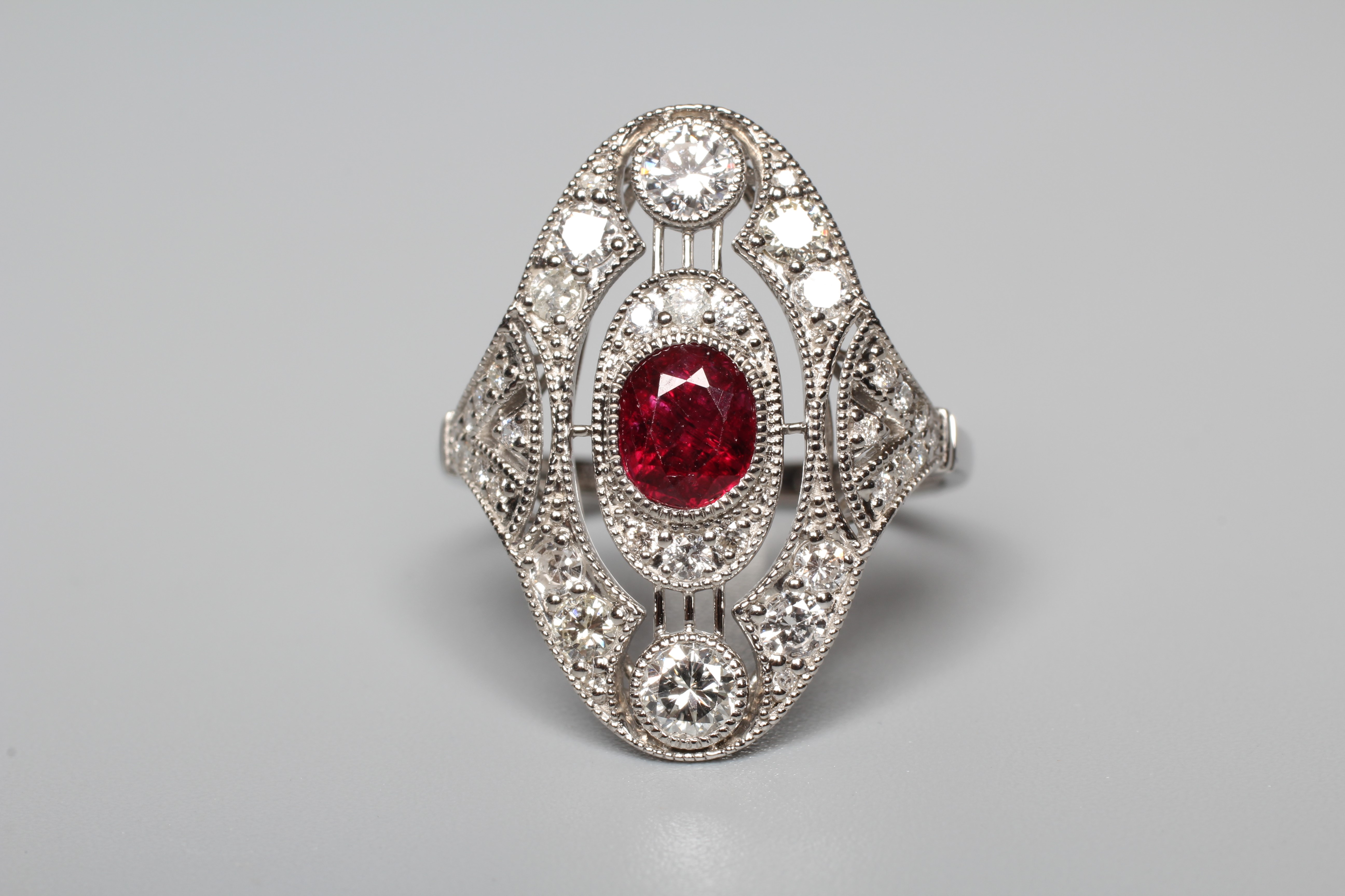 AN ART DECO STYLE RUBY AND DIAMOND PLAQUE RING, the central oval facet cut ruby collet set to an Image