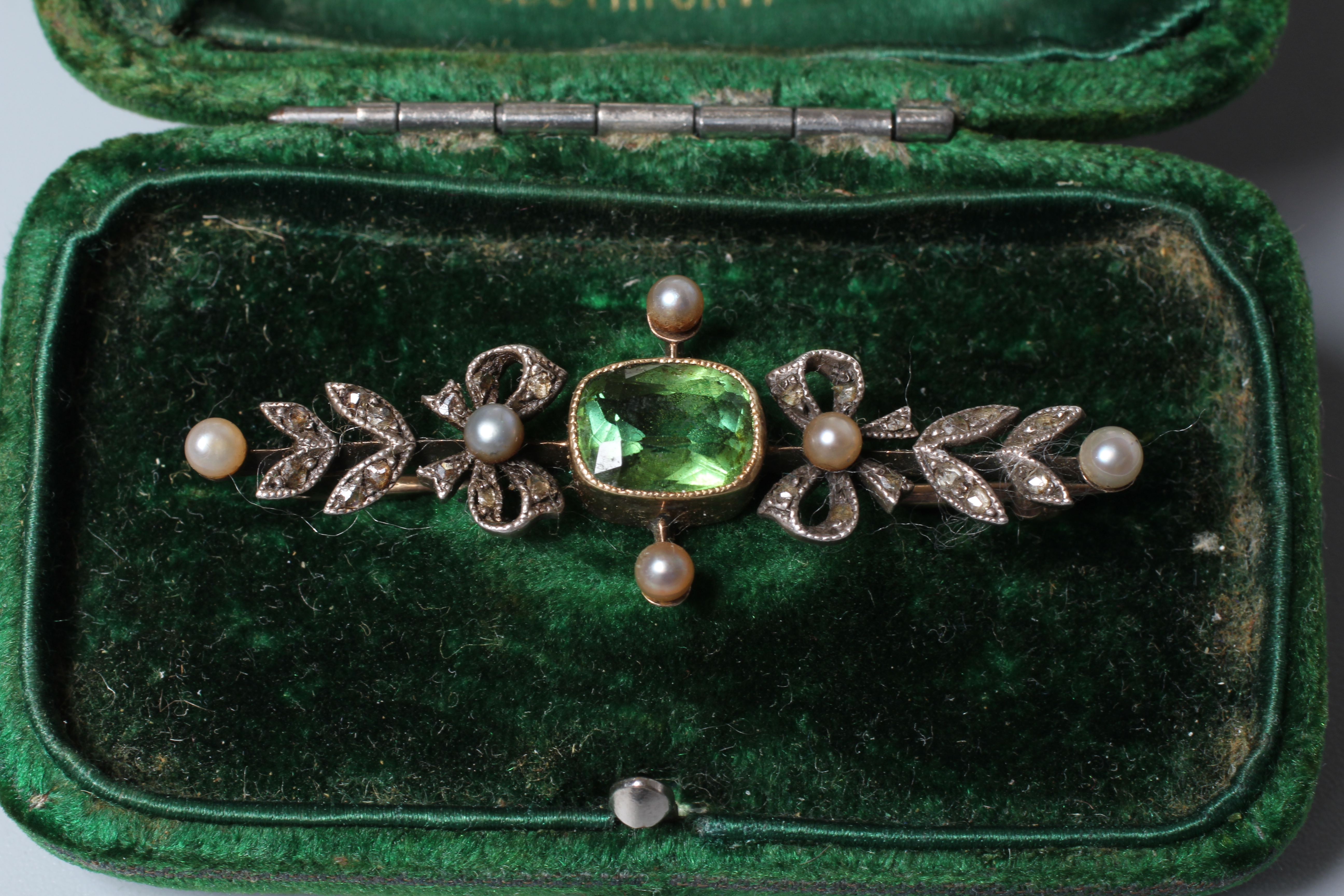 A VICTORIAN PERIDOT AND DIAMOND BROOCH, the facet cut oblong peridot open back collet set to rose Image
