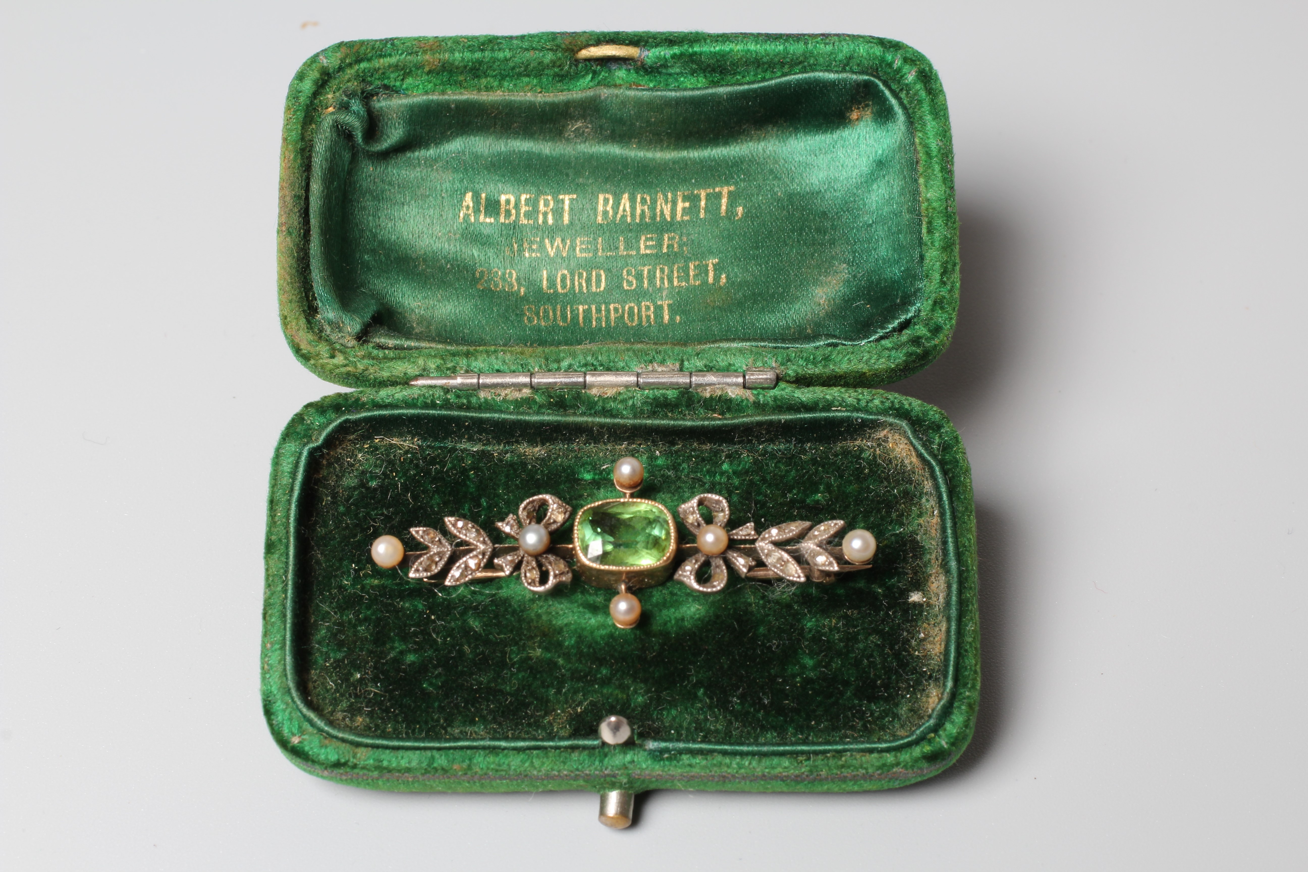 A VICTORIAN PERIDOT AND DIAMOND BROOCH, the facet cut oblong peridot open back collet set to rose Image
