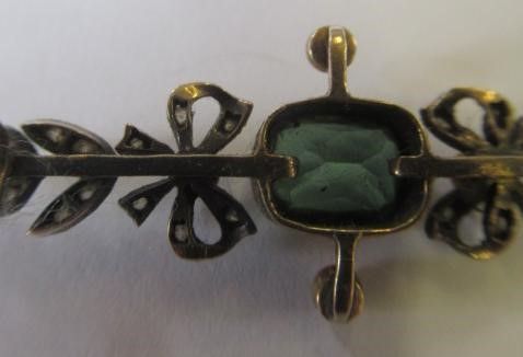 A VICTORIAN PERIDOT AND DIAMOND BROOCH, the facet cut oblong peridot open back collet set to rose Image