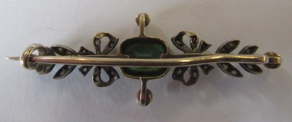 A VICTORIAN PERIDOT AND DIAMOND BROOCH, the facet cut oblong peridot open back collet set to rose Image