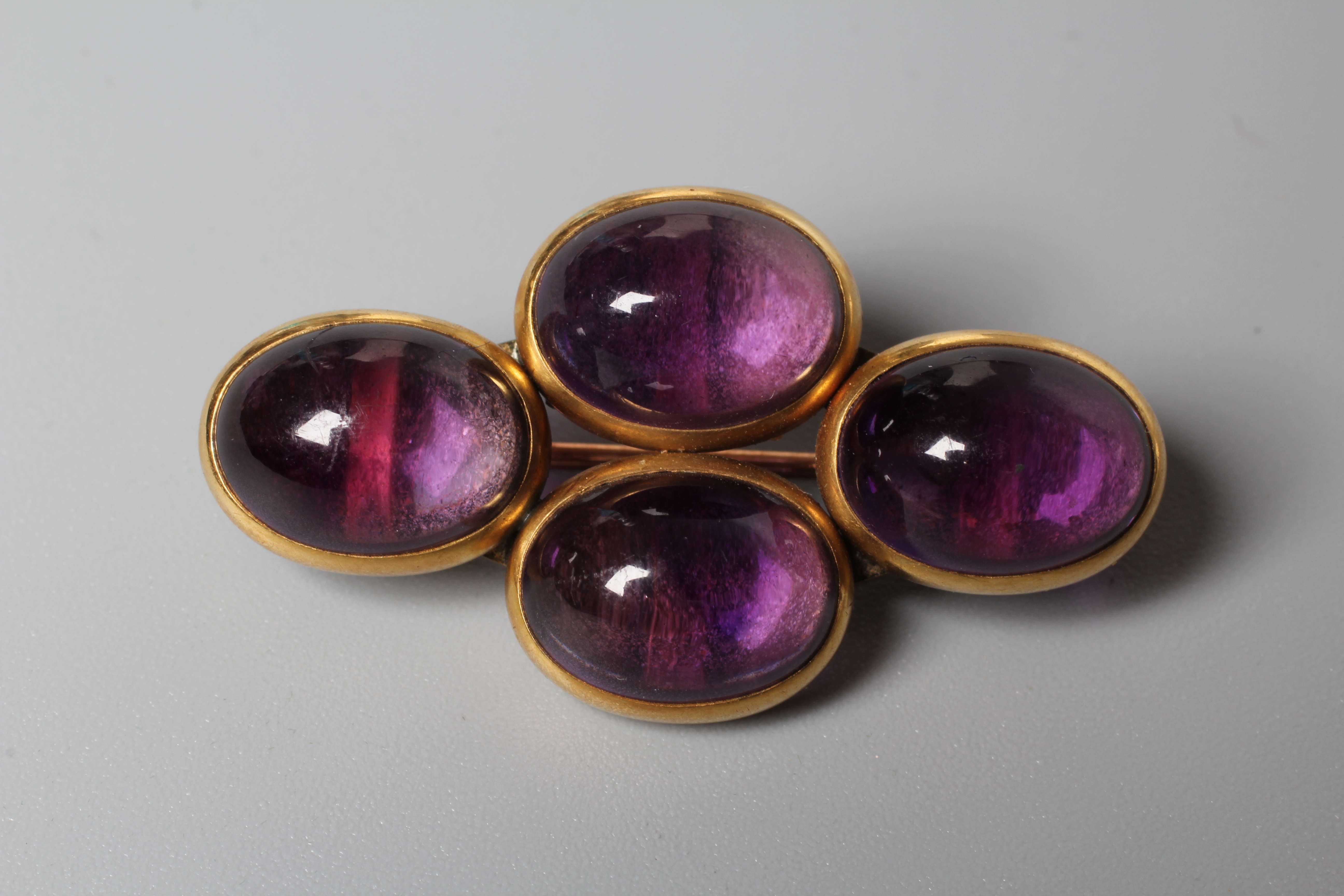 A VICTORIAN AMETHYST BROOCH, the four oval cabochon polished stones open back collet set to a plain Image