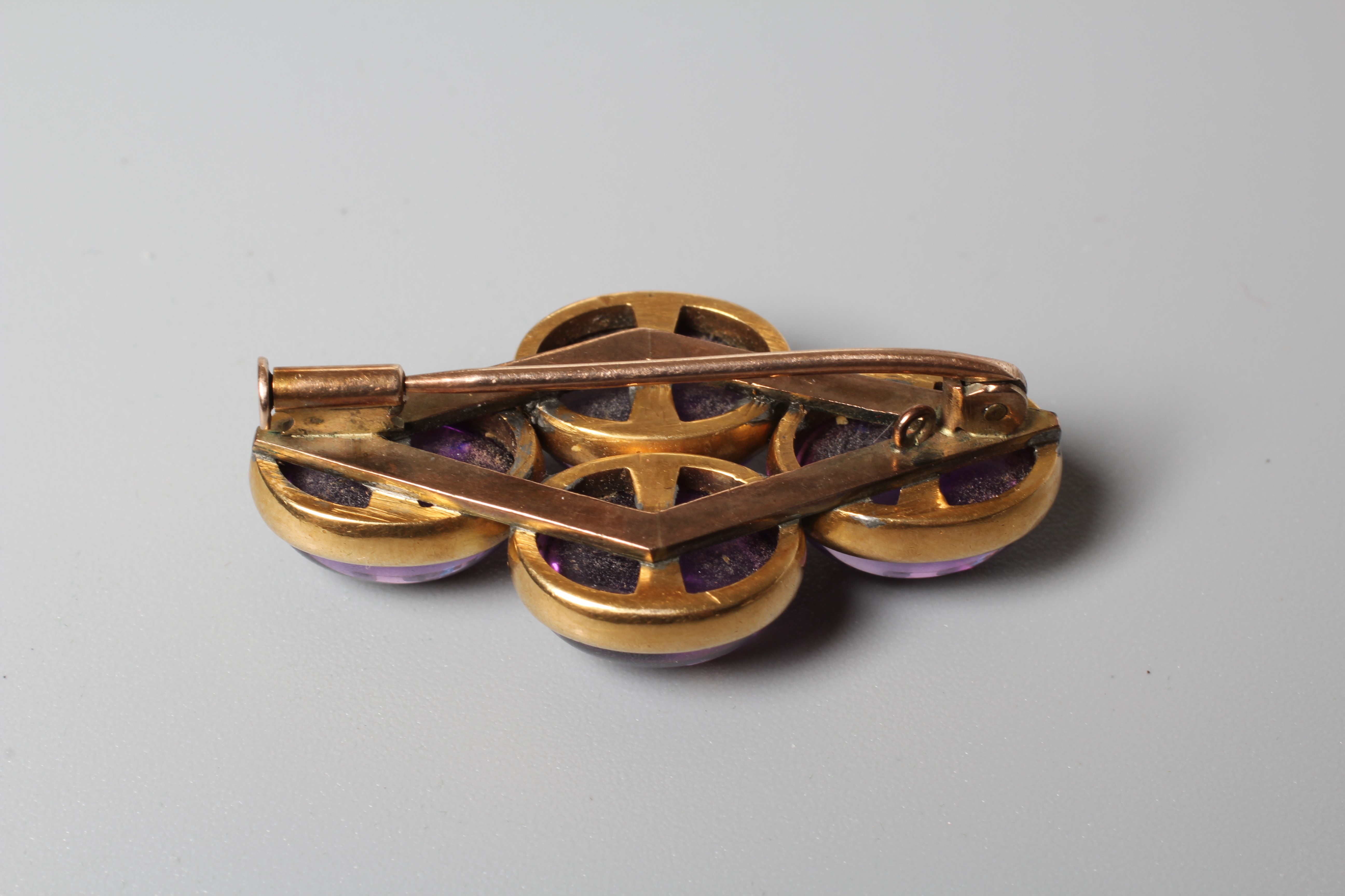 A VICTORIAN AMETHYST BROOCH, the four oval cabochon polished stones open back collet set to a plain Image