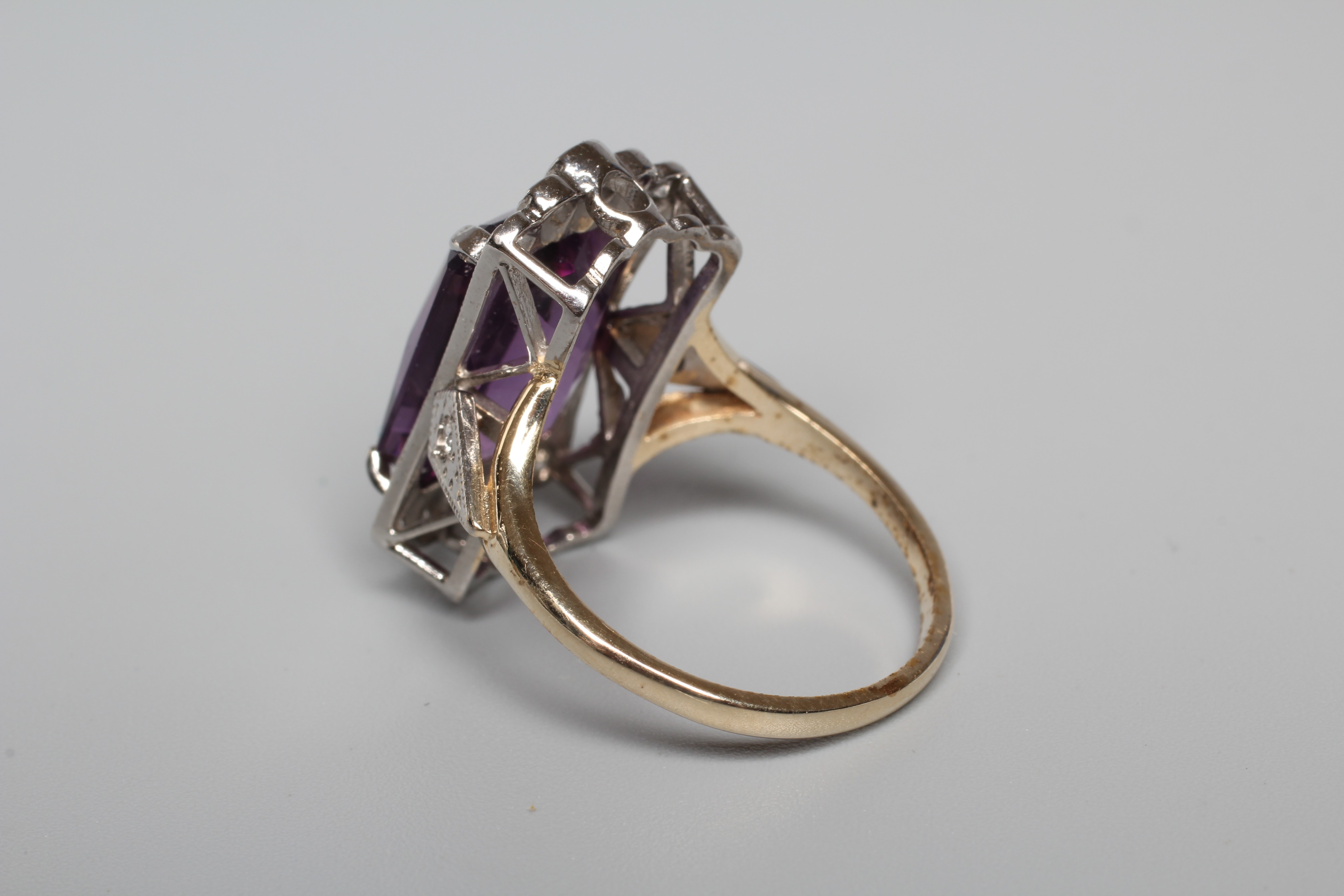 AN AMETHYST AND DIAMOND COCKTAIL RING, the emerald cut amethyst claw set to diamond angles and Image