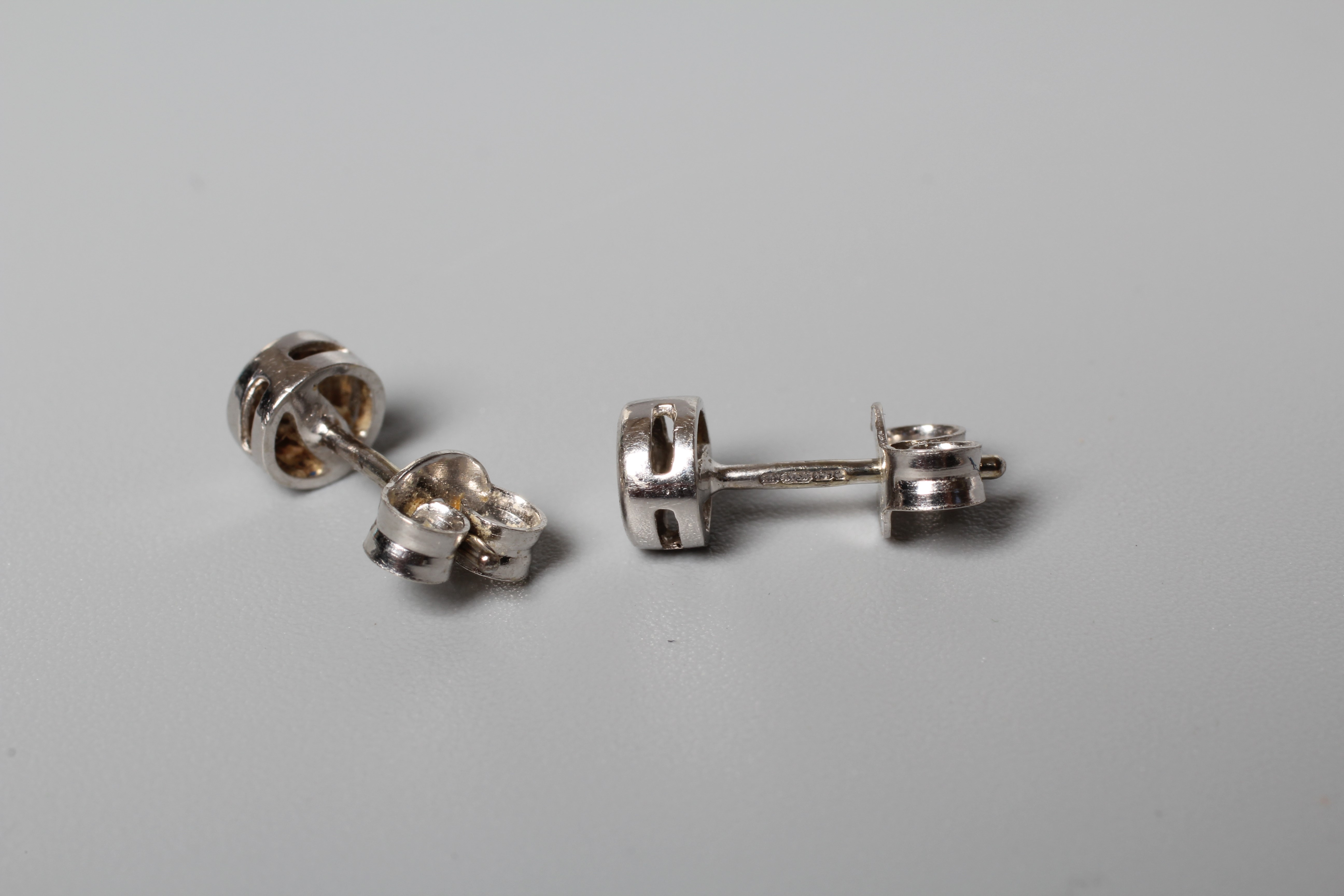 A PAIR OF DIAMOND SOLITAIRE EAR STUDS, the small round brilliant cut stones in rub over settings to Image