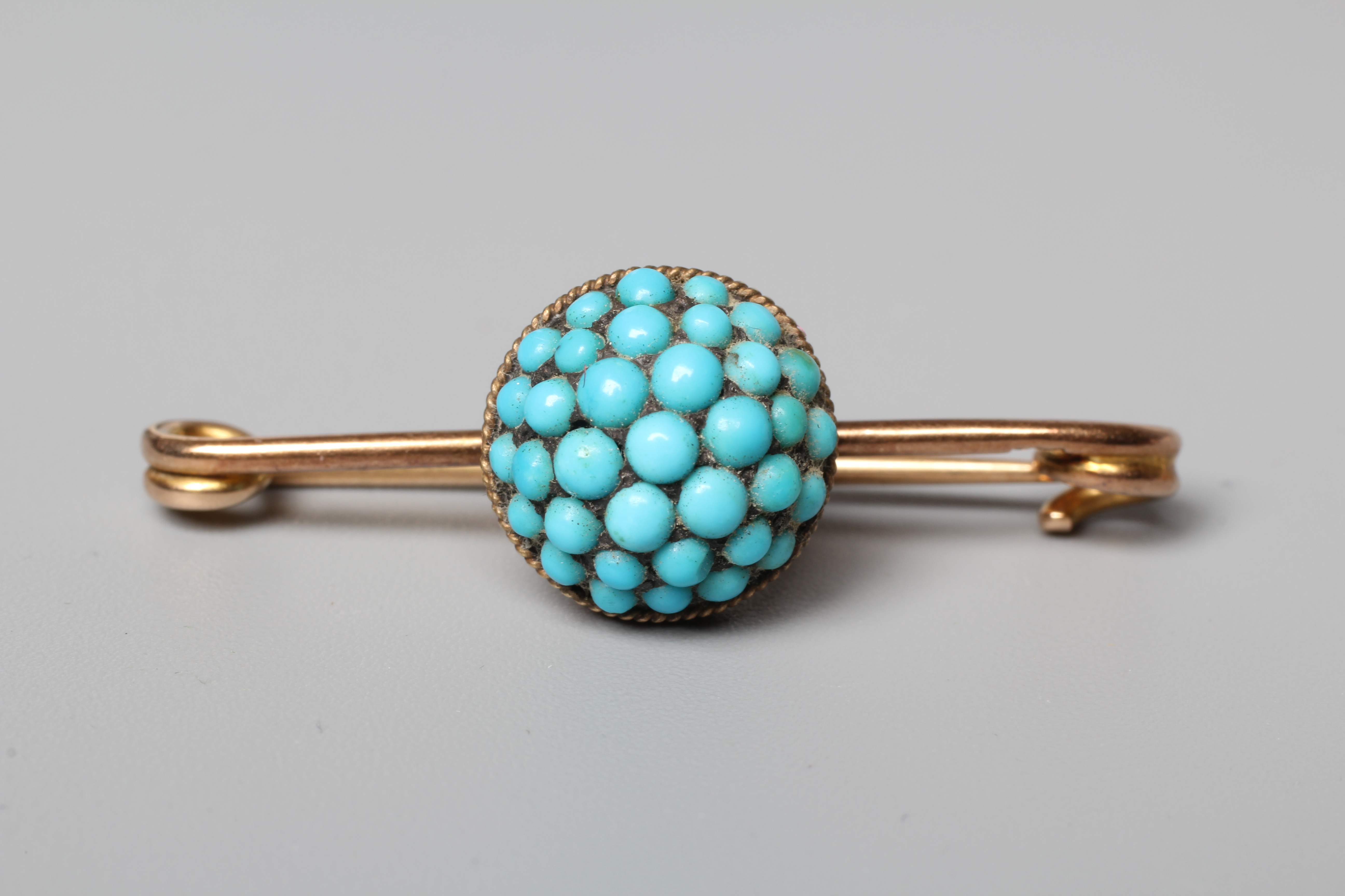 A LATE VICTORIAN BAR BROOCH centred by a turquoise bead set boss, stamped 15ct Image