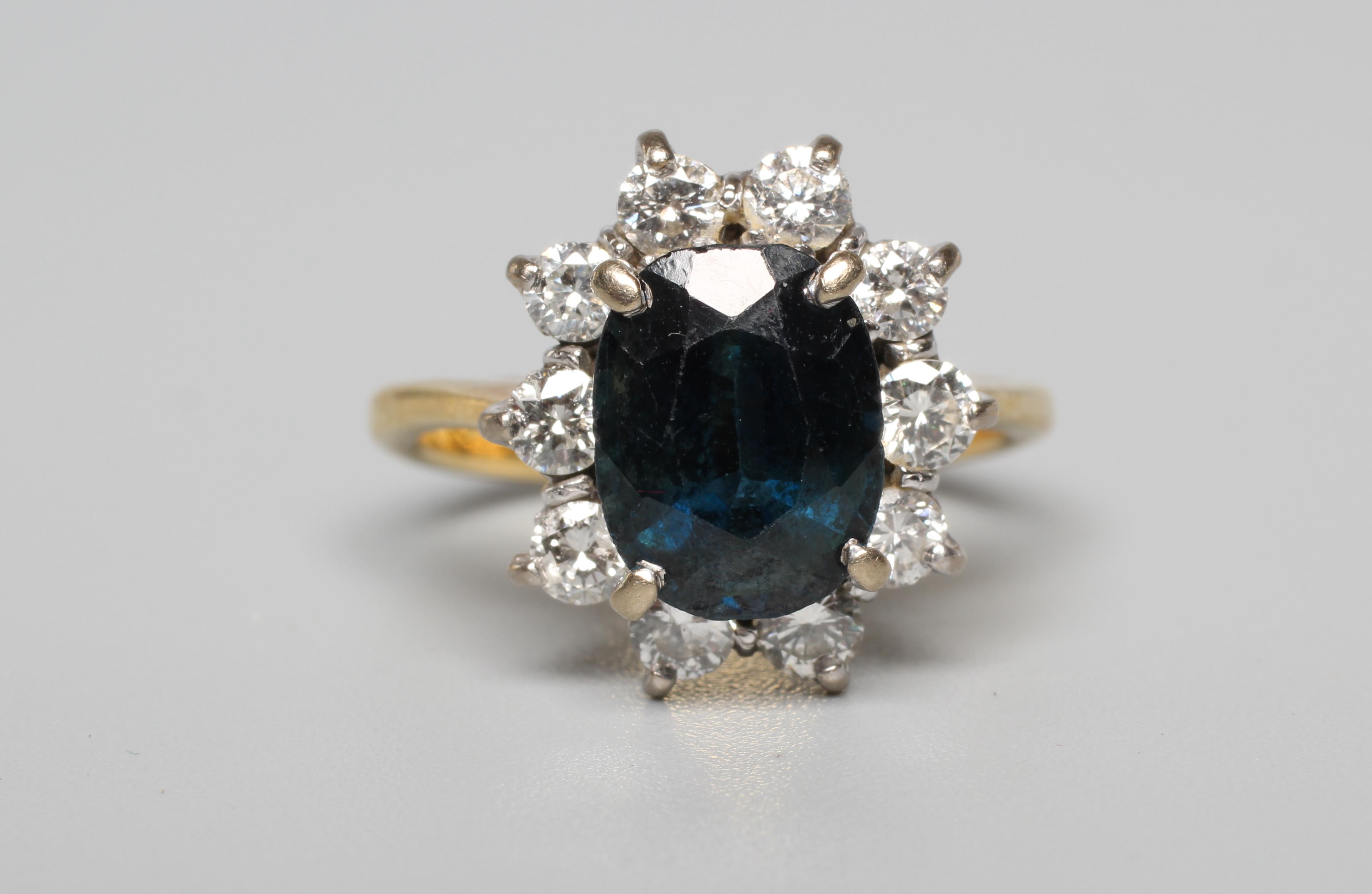 A SAPPHIRE AND DIAMOND CLUSTER RING, the oval facet cut sapphire claw set to a border of ten round Image