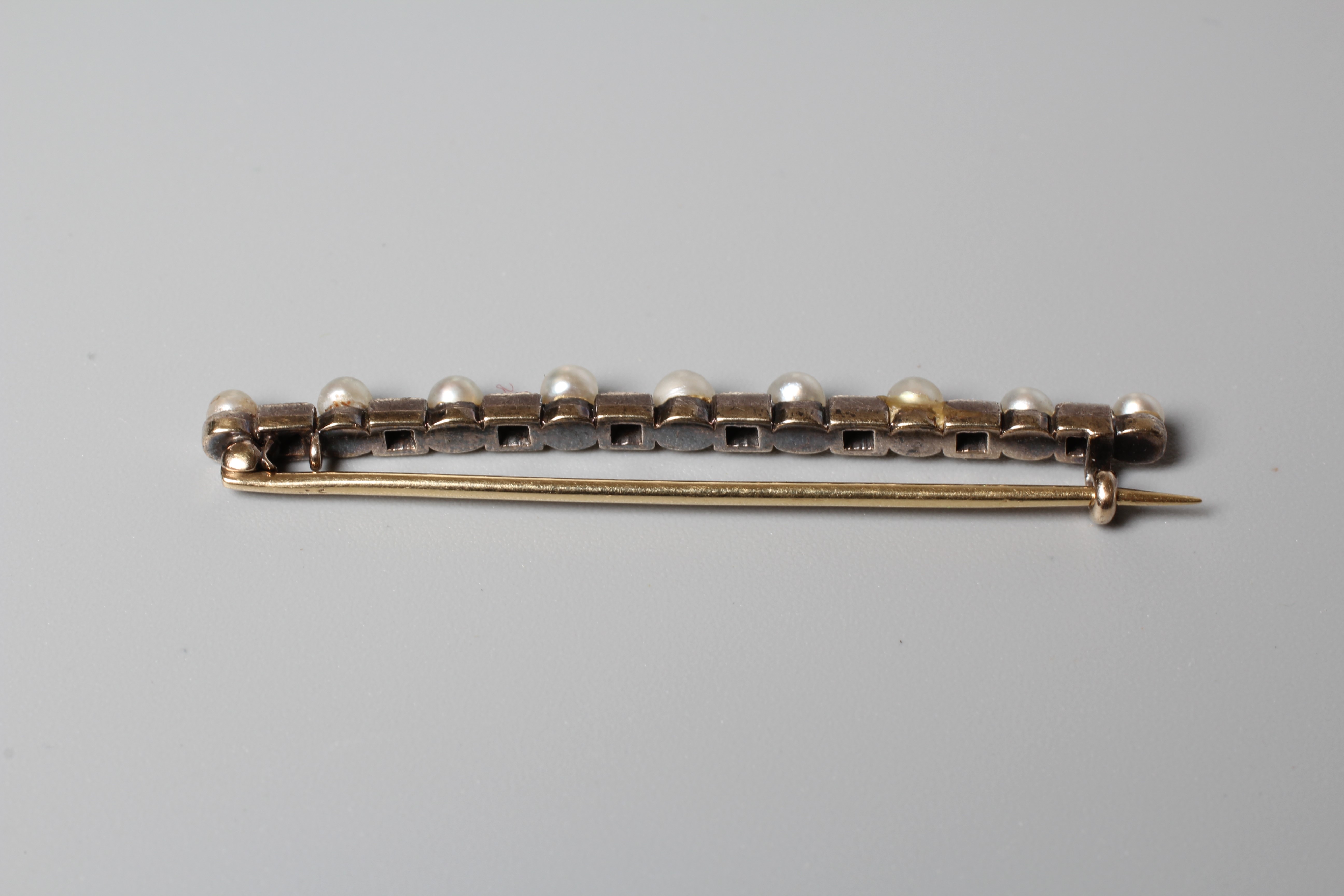 A VICTORIAN DIAMOND AND PEARL BAR BROOCH, the nine peg set pearls with eight rose cut diamonds Image