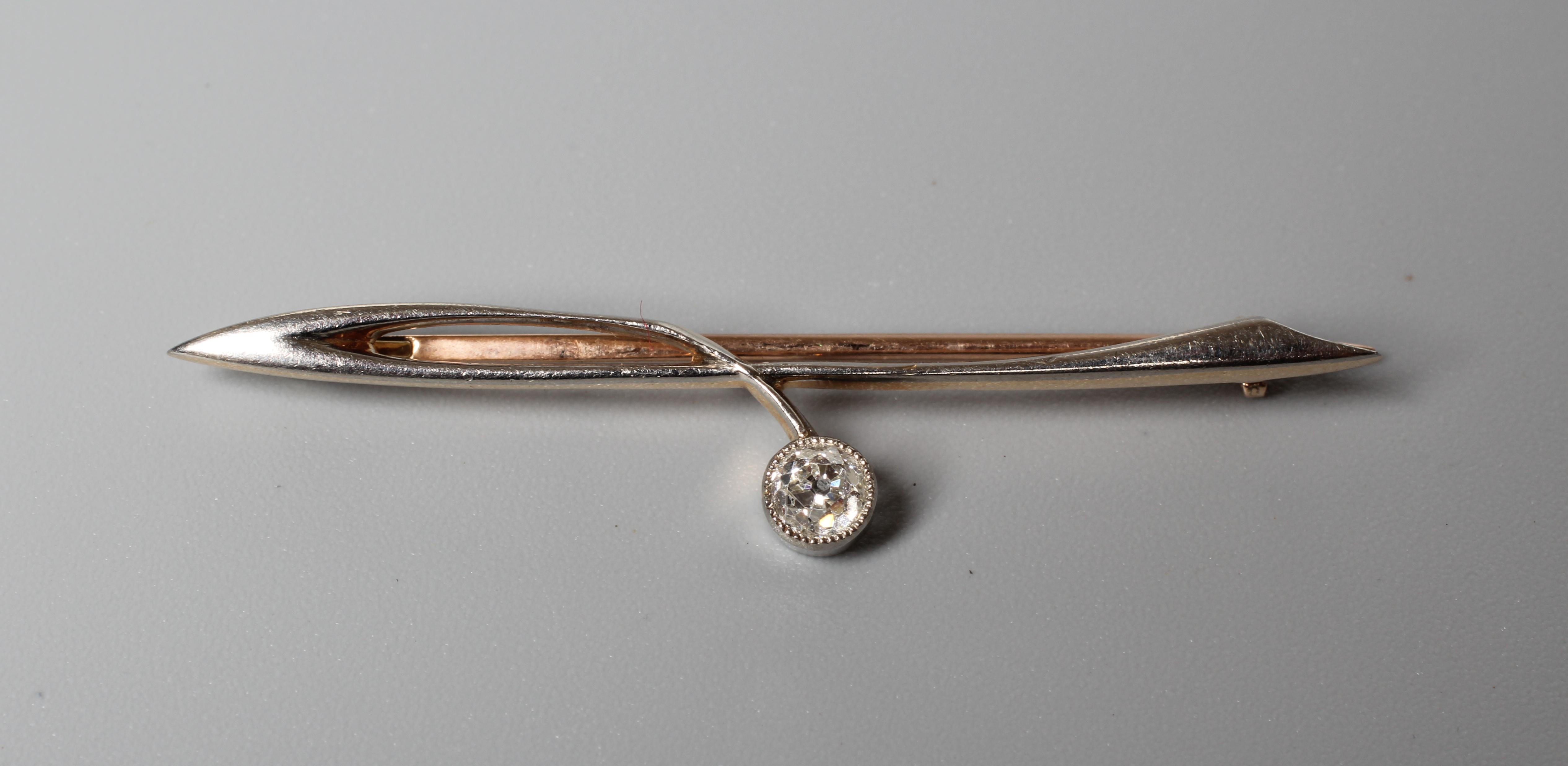 AN ART DECO SOLITAIRE DIAMOND BROOCH, the brilliant cut stone open back collet set to an abstract Image