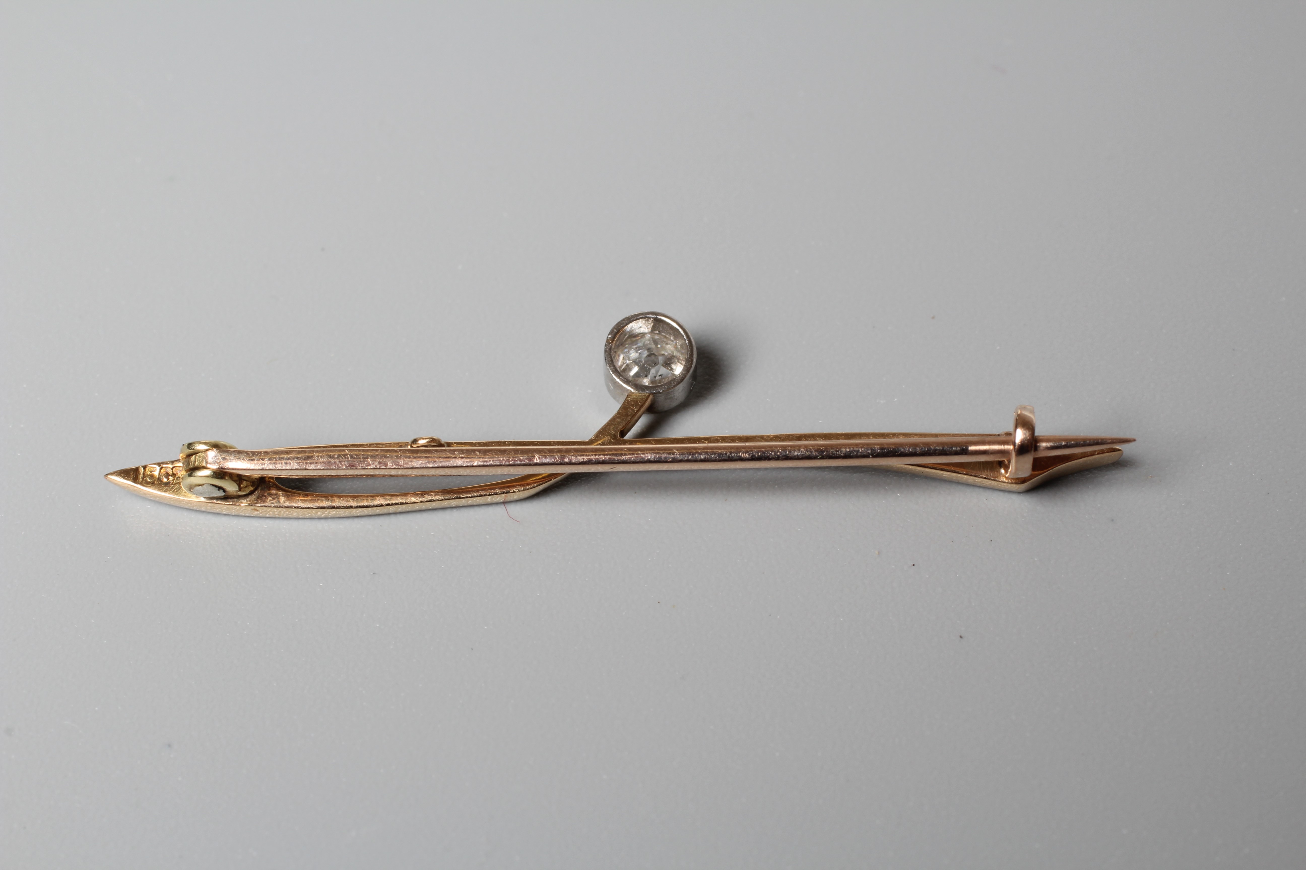 AN ART DECO SOLITAIRE DIAMOND BROOCH, the brilliant cut stone open back collet set to an abstract Image