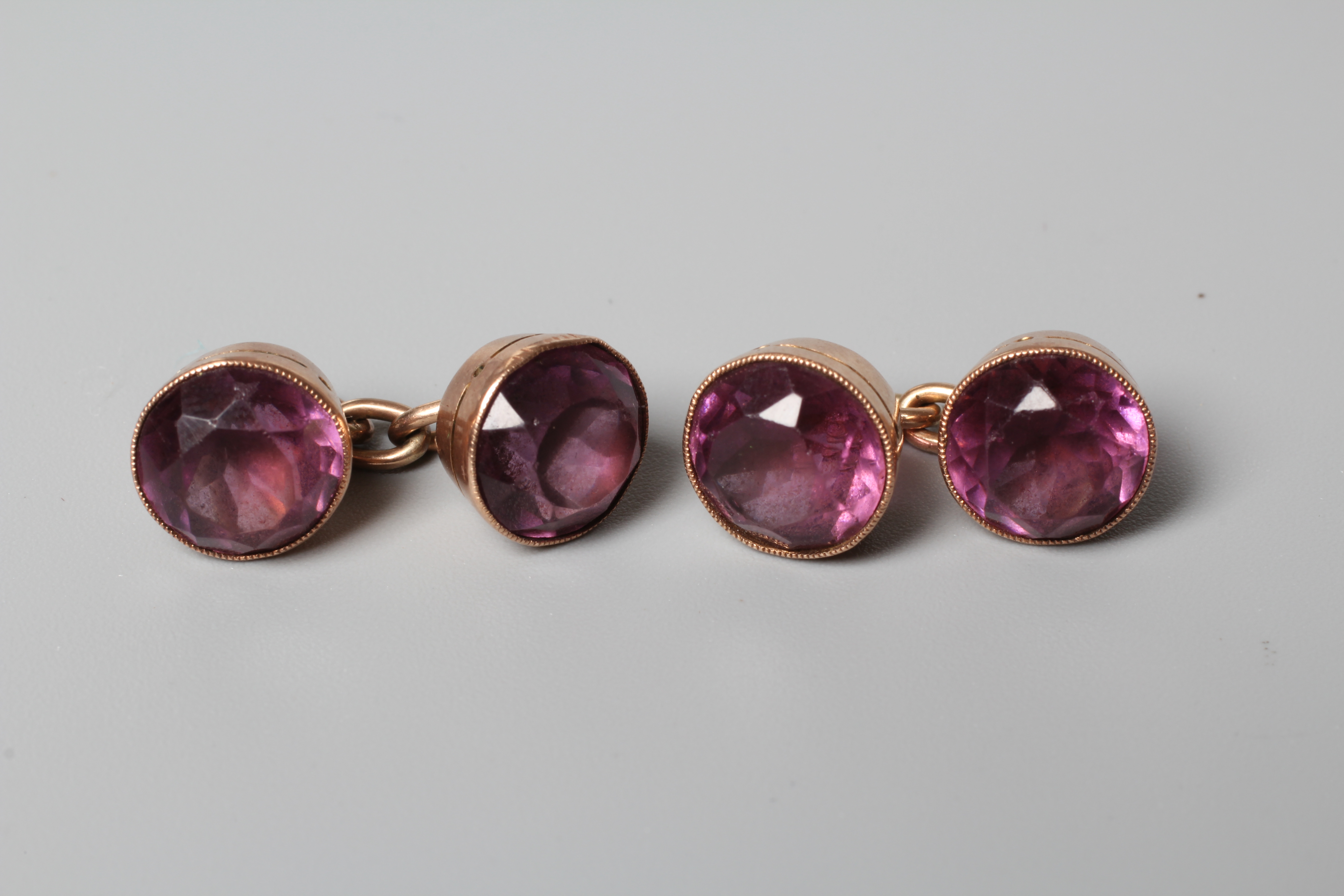 A PAIR OF VICTORIAN AMETHYST CUFFLINKS, the circular facet cut stones collet set to plain unmarked Image