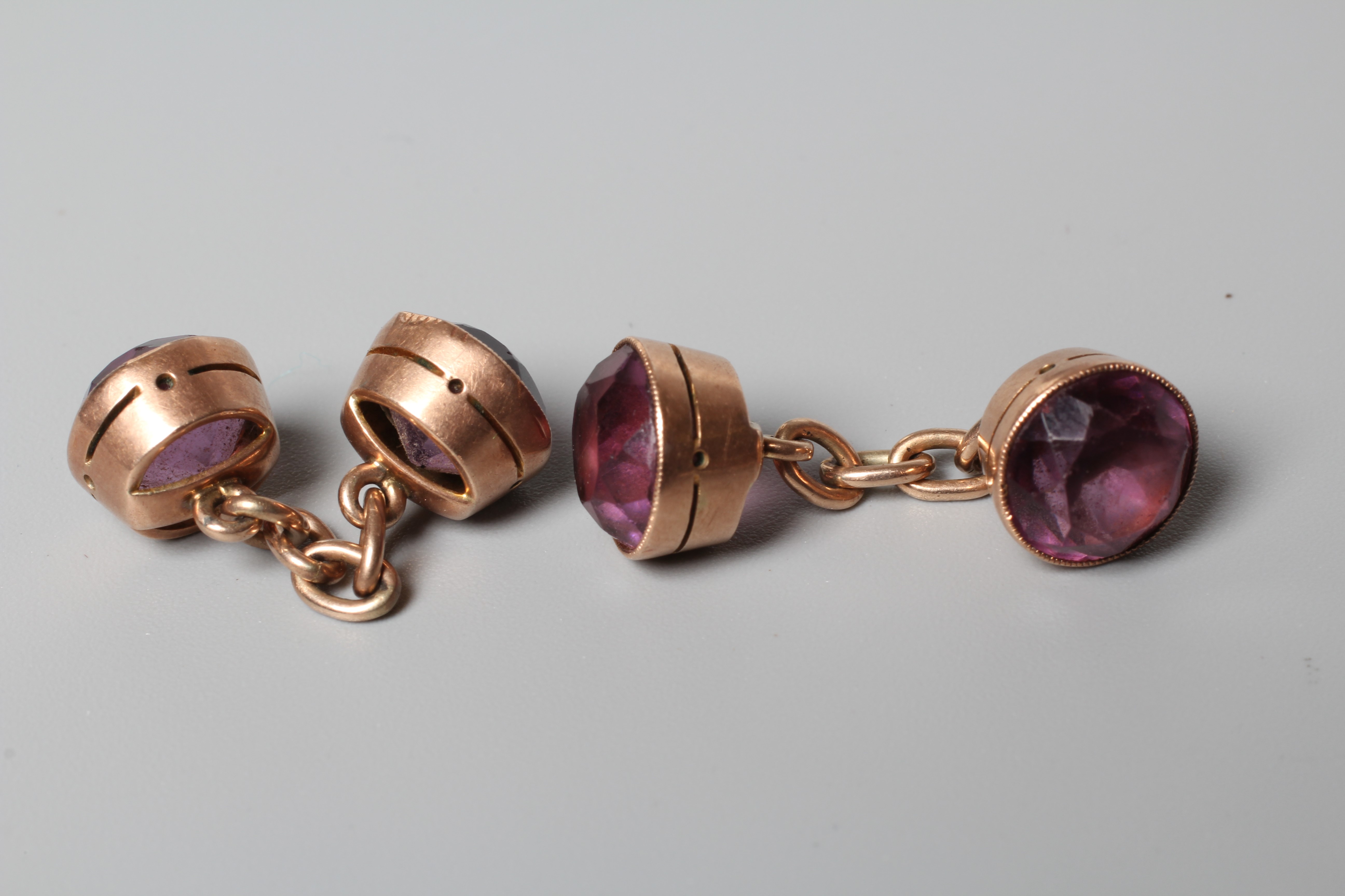 A PAIR OF VICTORIAN AMETHYST CUFFLINKS, the circular facet cut stones collet set to plain unmarked Image