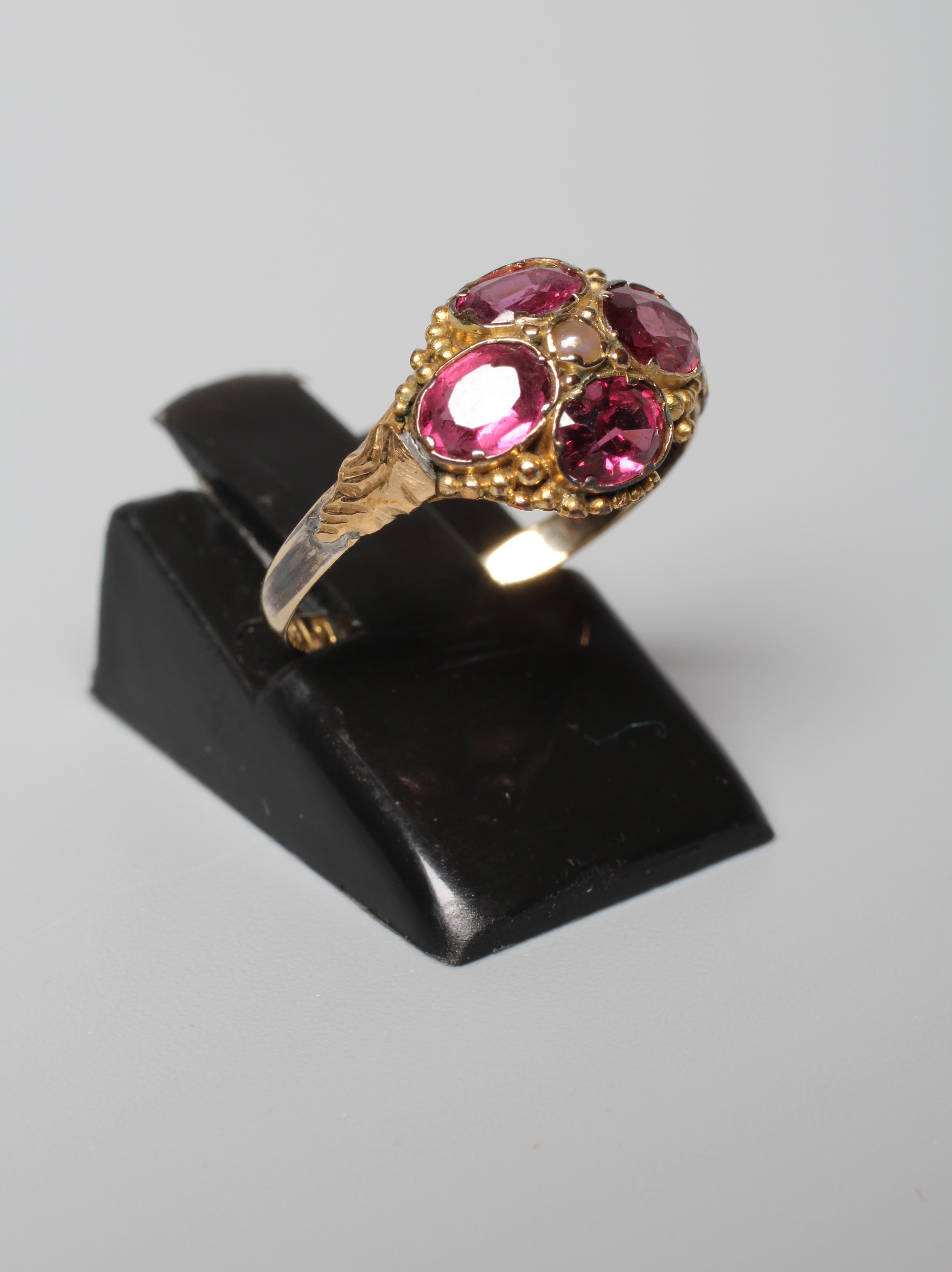 A LATE VICTORIAN ALMANDINE GARNET RING, the four oval facet cut stones collet set and centred by a Image