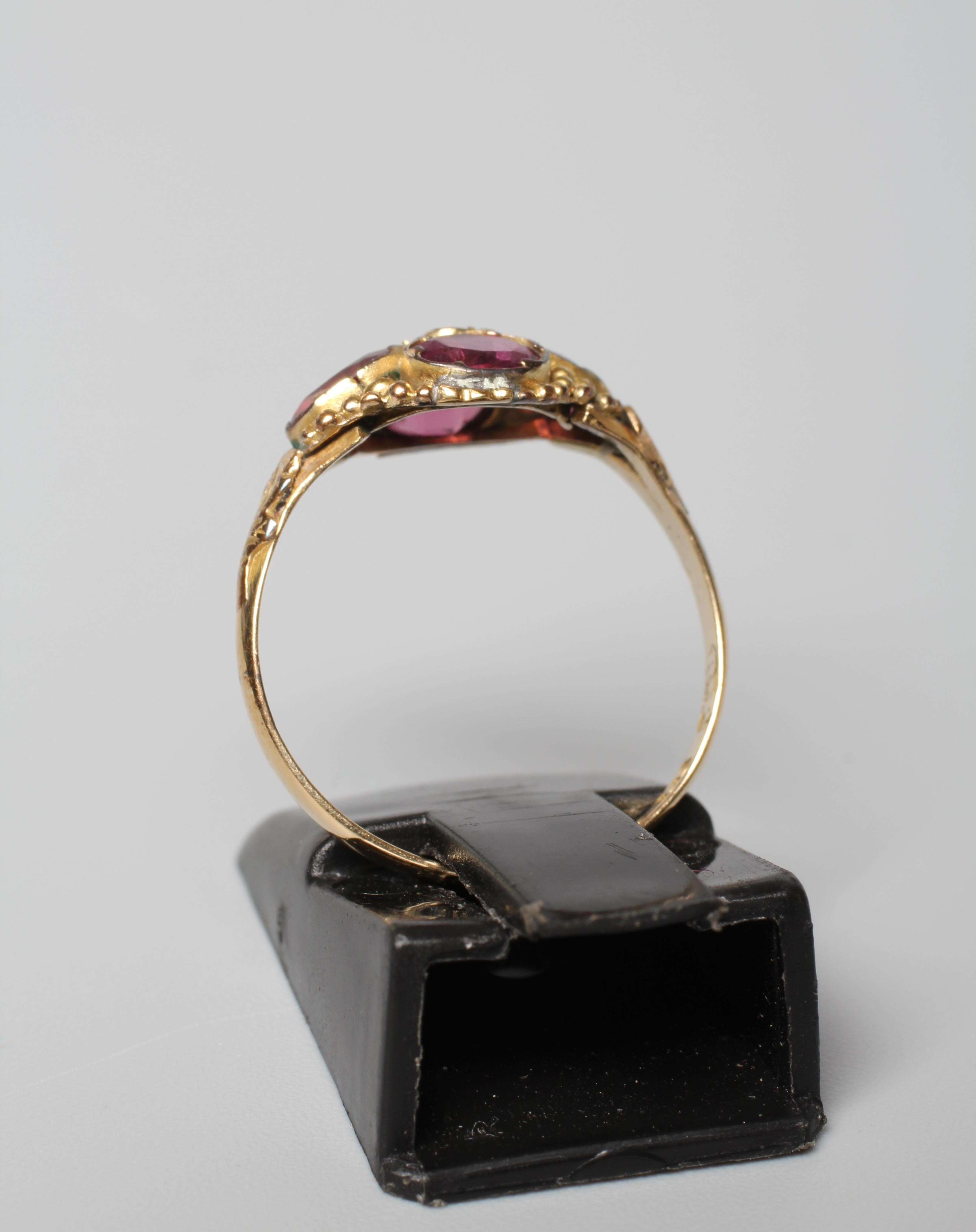 A LATE VICTORIAN ALMANDINE GARNET RING, the four oval facet cut stones collet set and centred by a Image