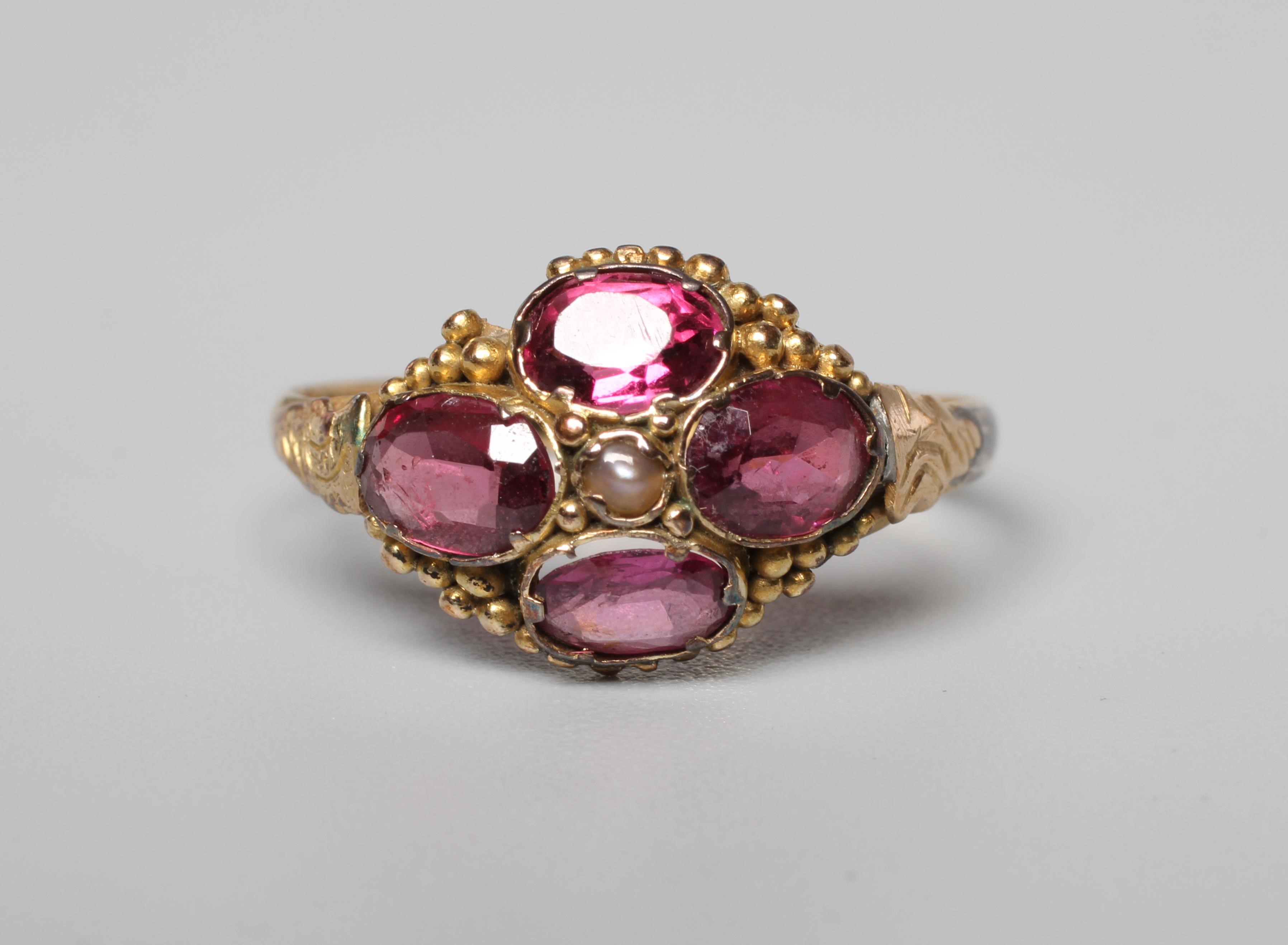 A LATE VICTORIAN ALMANDINE GARNET RING, the four oval facet cut stones collet set and centred by a Image