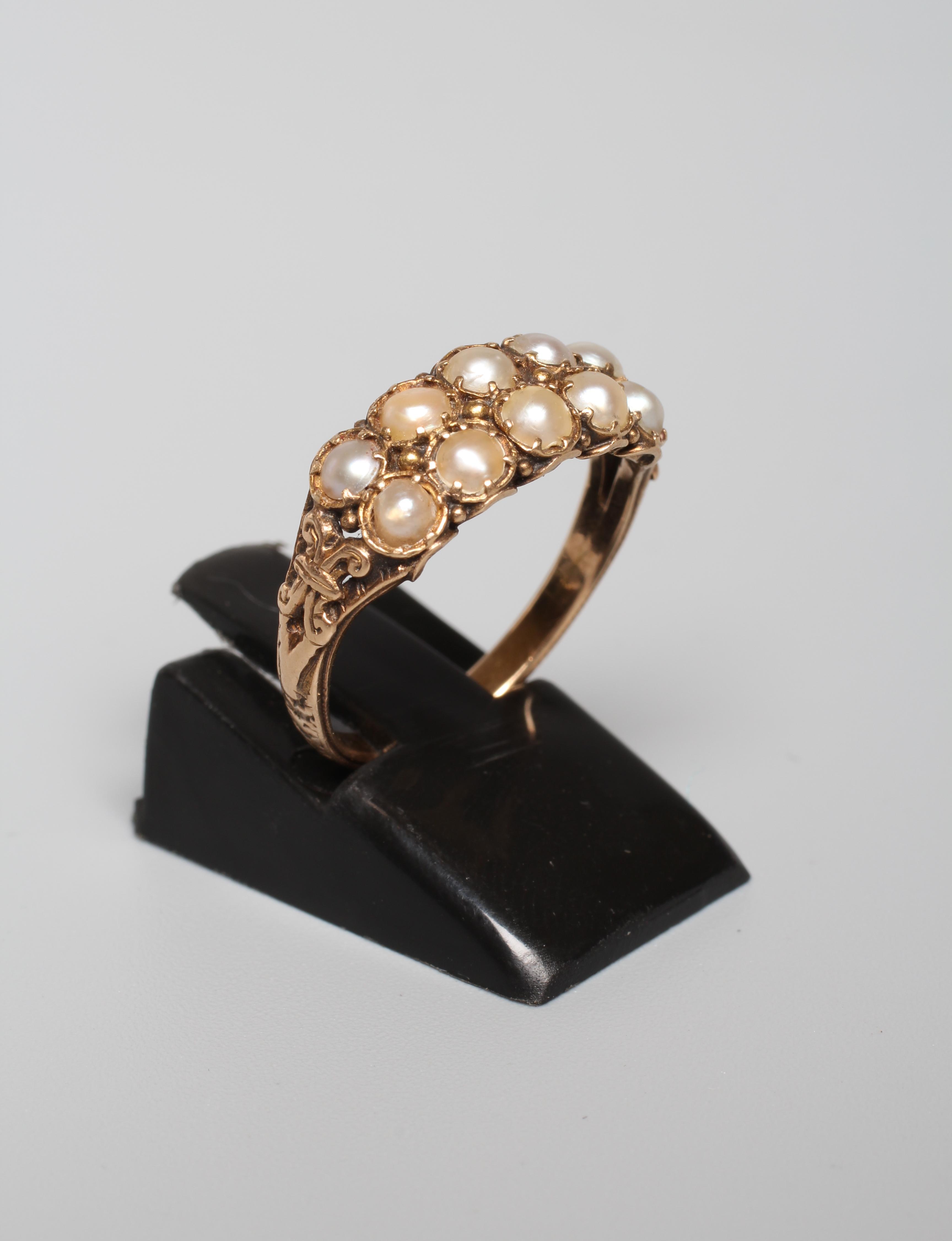 A VICTORIAN TWO ROW PEARL RING, the ten small pearls set in pairs to carved open shoulders and a Image
