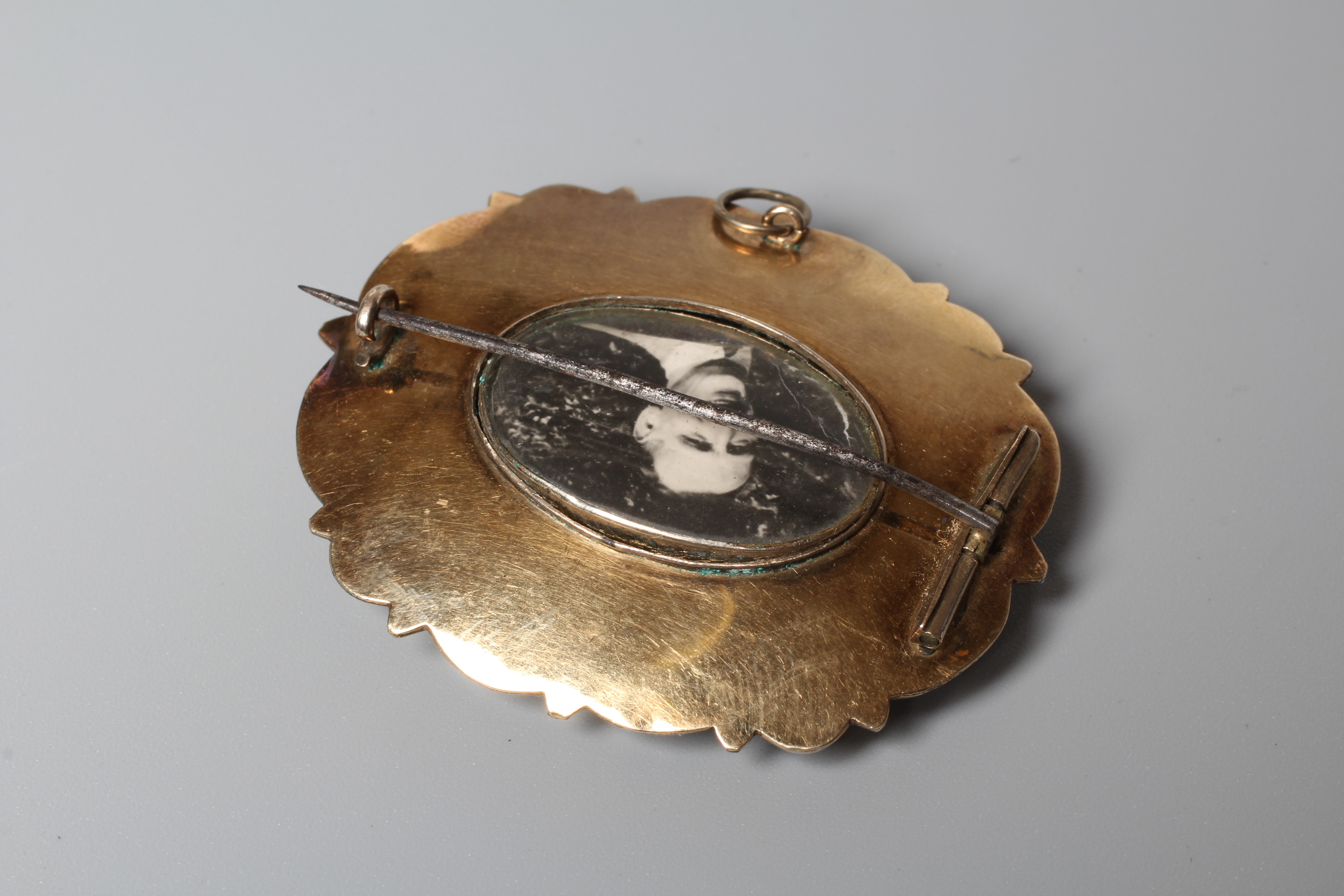 A VICTORIAN OVAL BROOCH, the green guilloche enamel ground overlaid with a scrolling border Image
