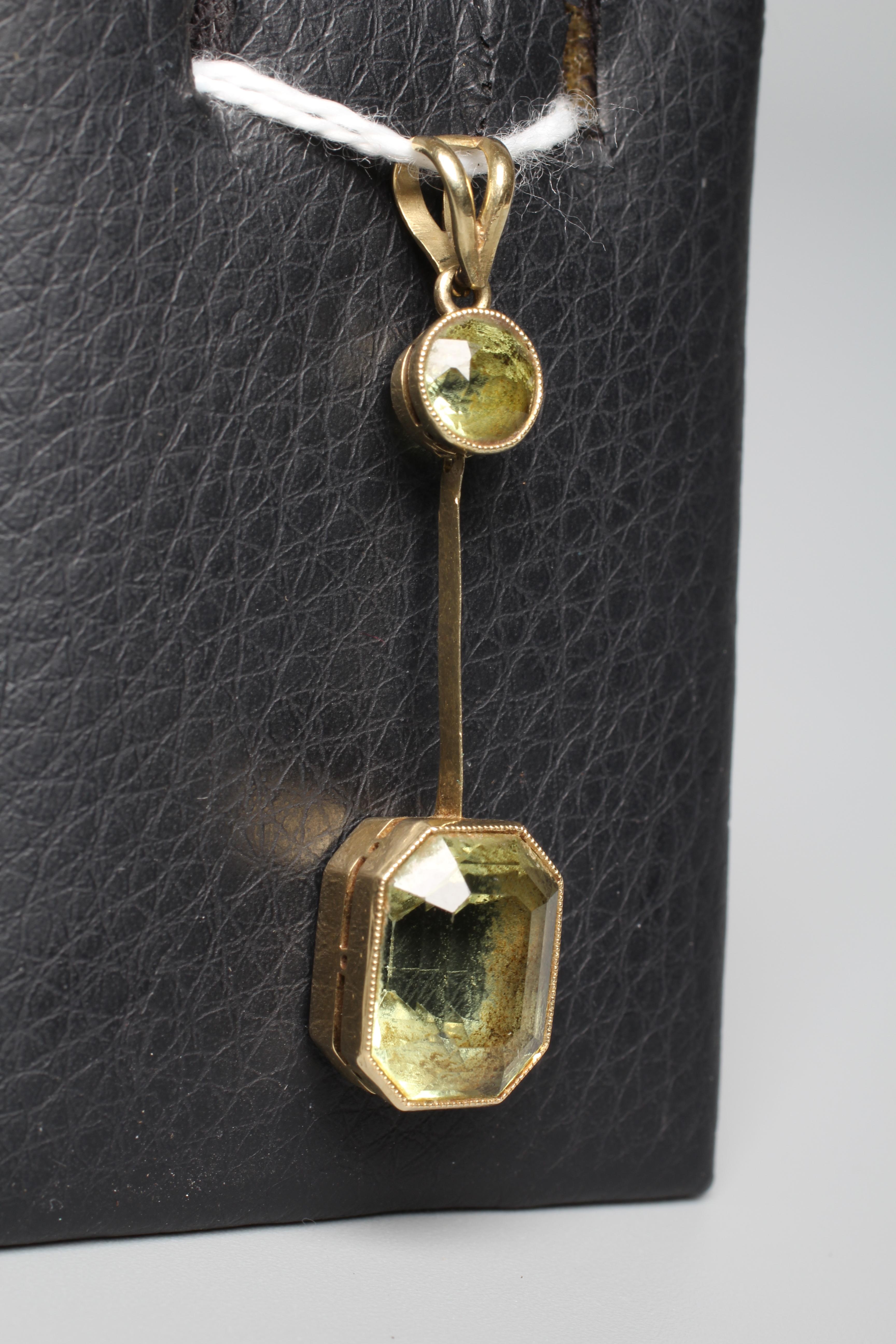 AN EDWARDIAN PERIDOT PENDANT, the step cut stone fixed to a knife edge bar hung from a circular open Image