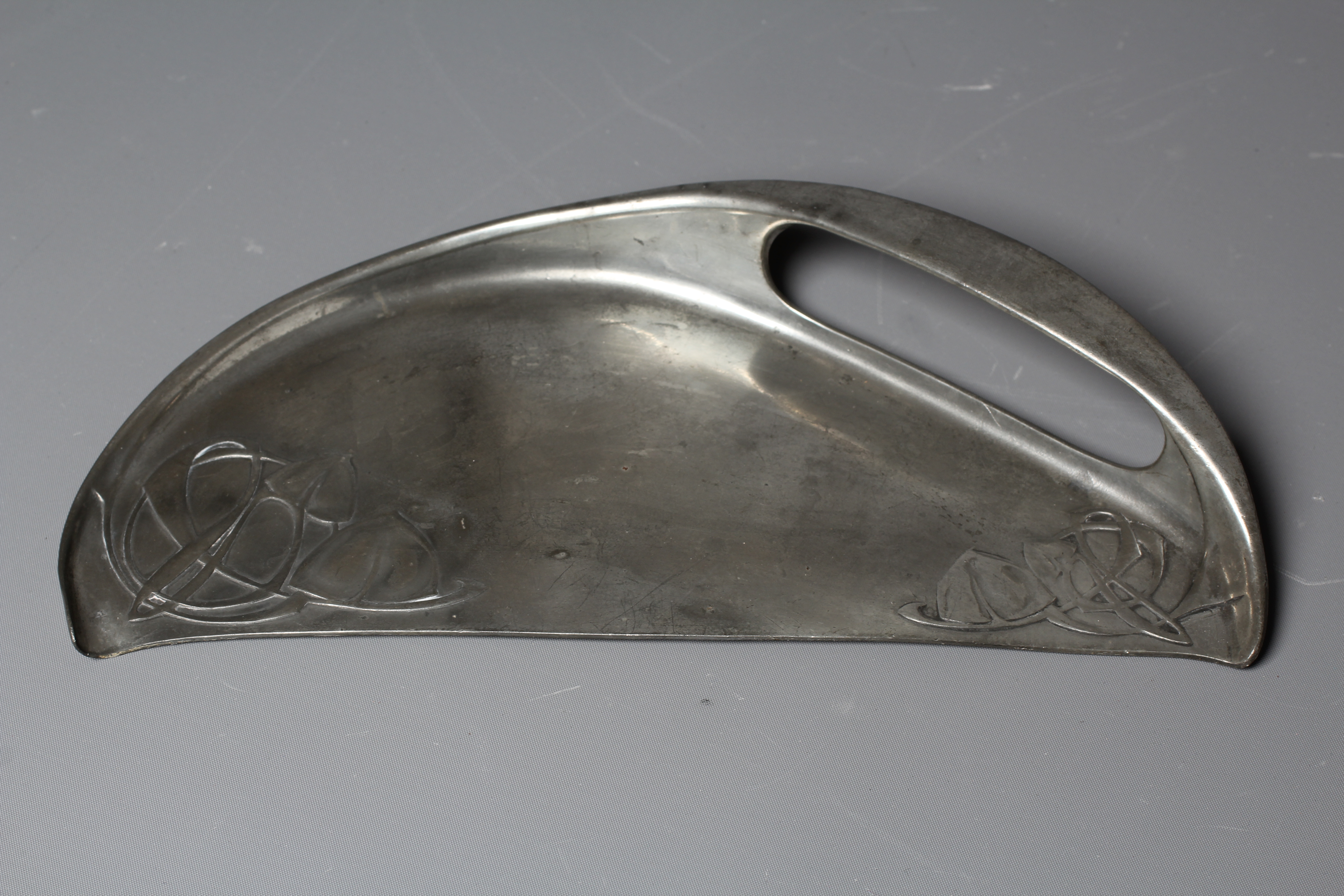 ARCHIBALD KNOX FOR LIBERTY & CO. - An English Pewter demi-lune crumb tray cast with two panels of Image