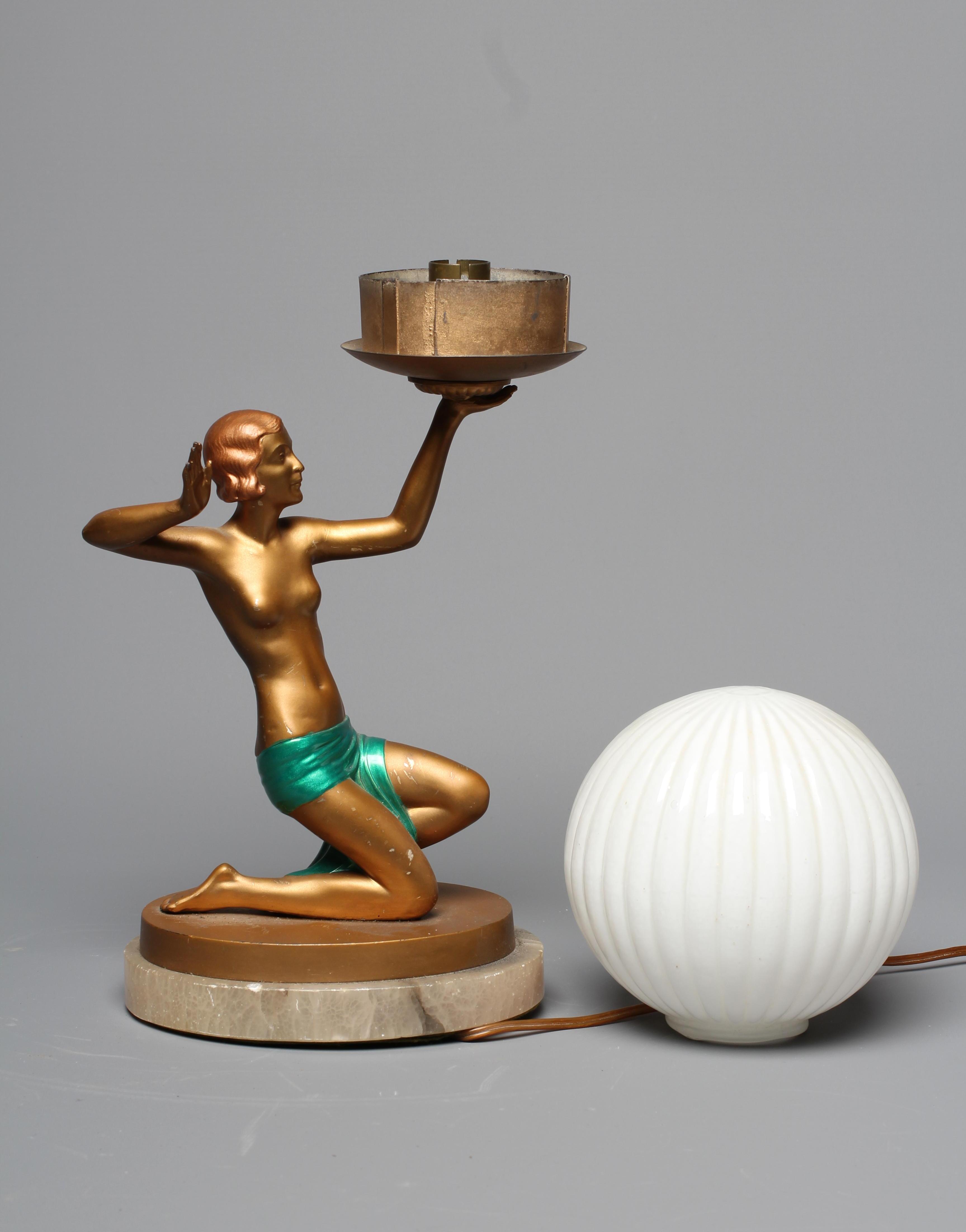 AN ART DECO GILT PATINATED SPELTER FIGURAL TABLE LAMP, the female in pose holding a light fitting Image