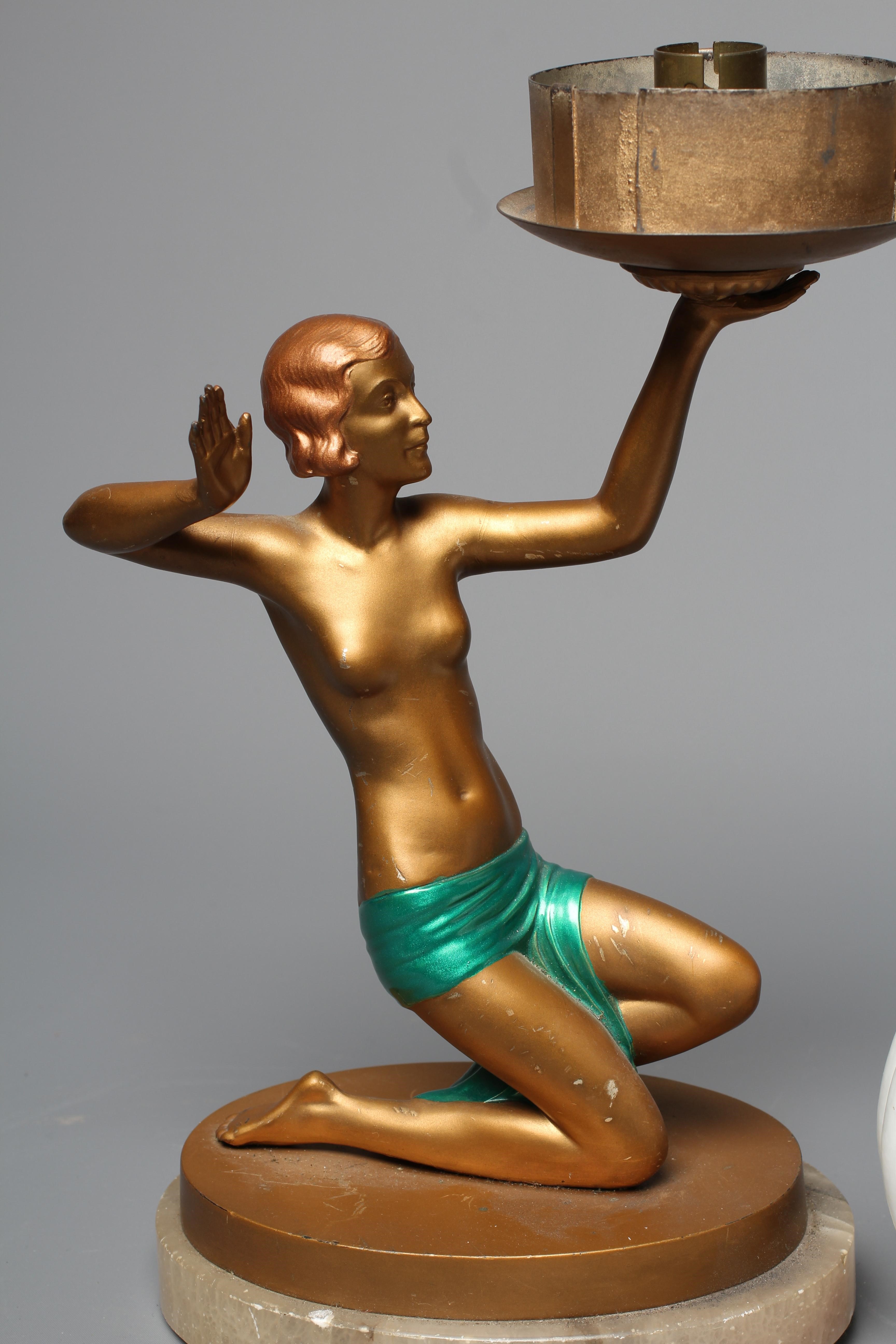 AN ART DECO GILT PATINATED SPELTER FIGURAL TABLE LAMP, the female in pose holding a light fitting Image