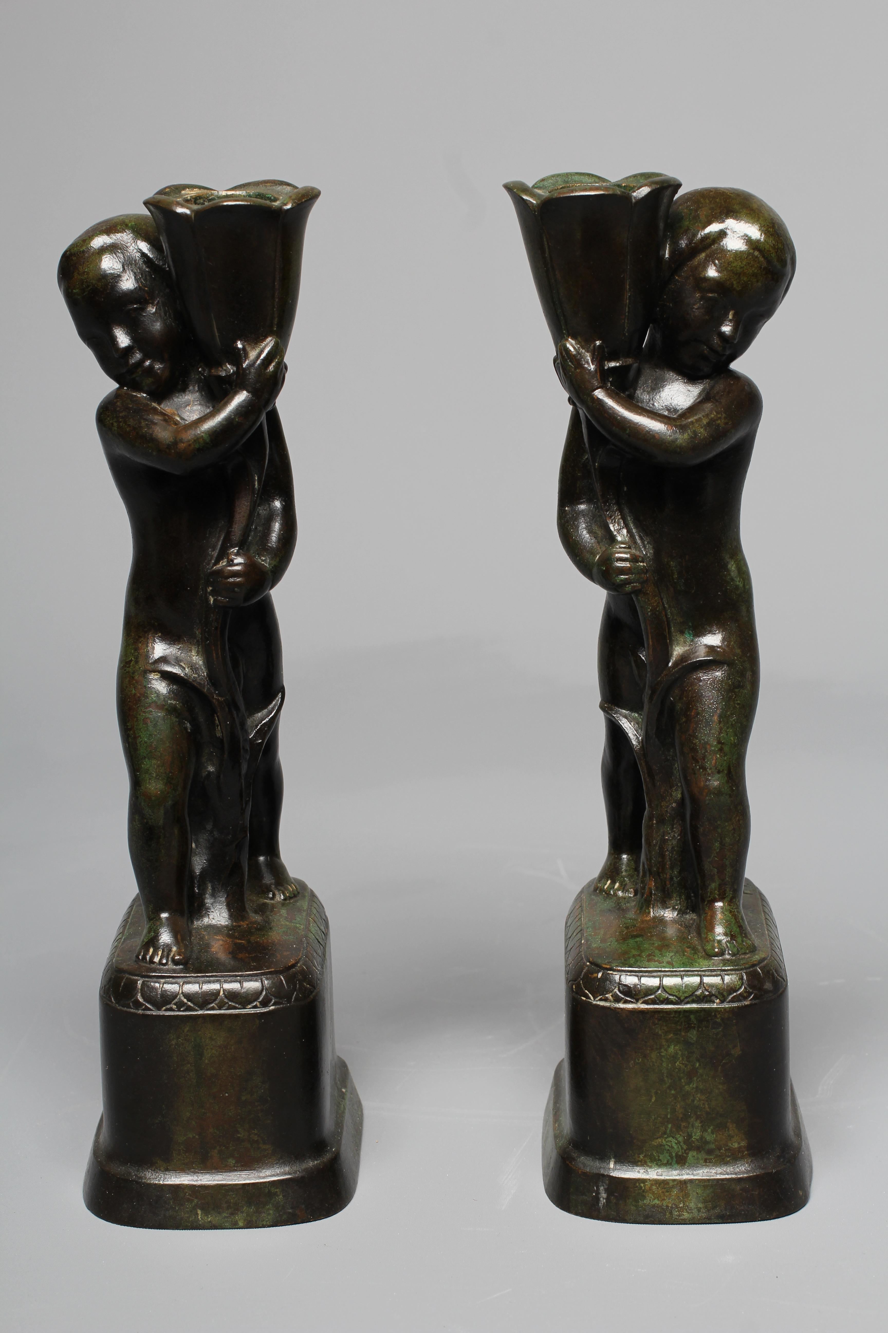 STYLE OF PIERRE TRAVERSE (1892-1979) A pair of candlesticks modelled as children holding stylised Image