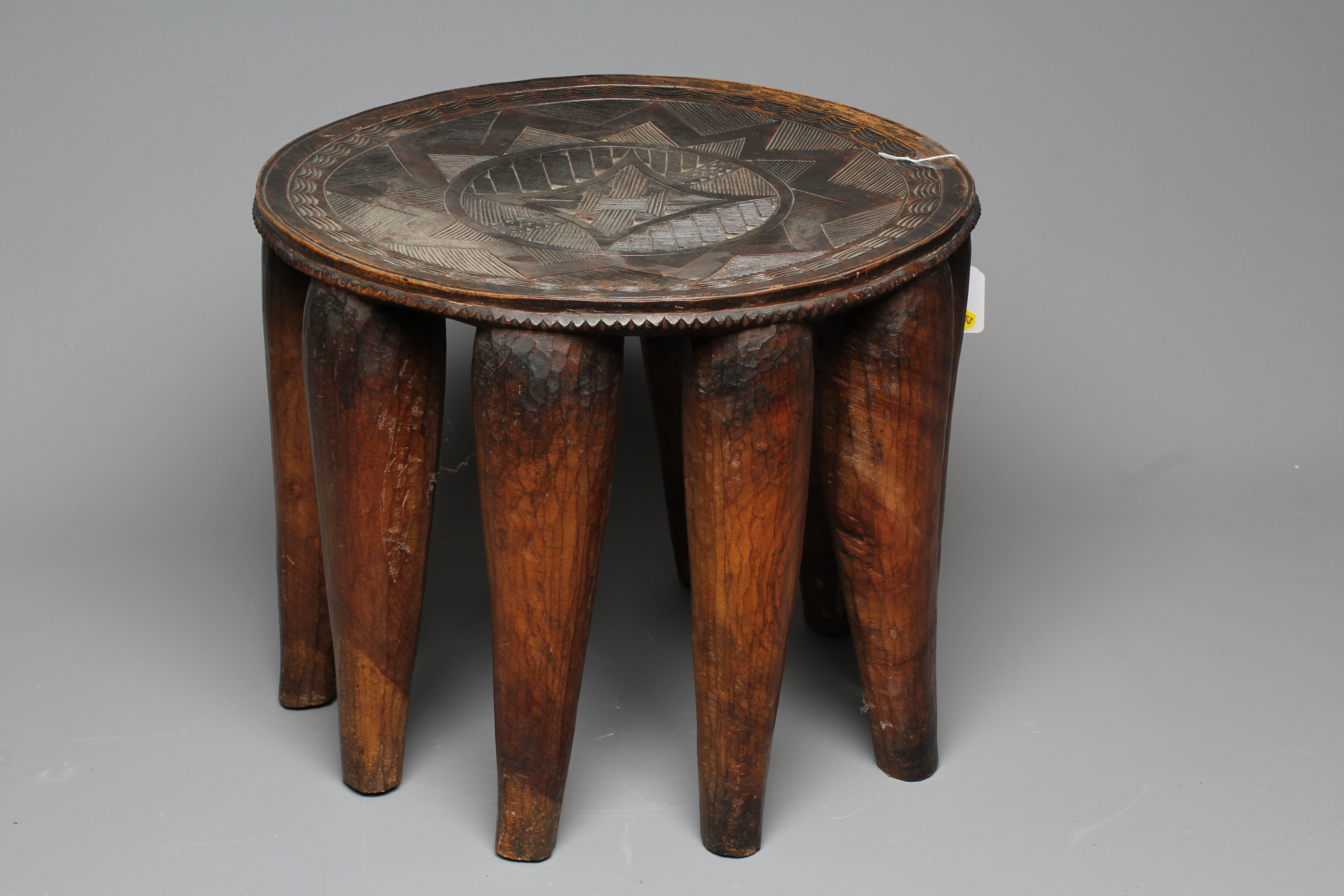 A NUPE TRIBAL STOOL, the circular top decorated with a geometric design raised on ten circular Image