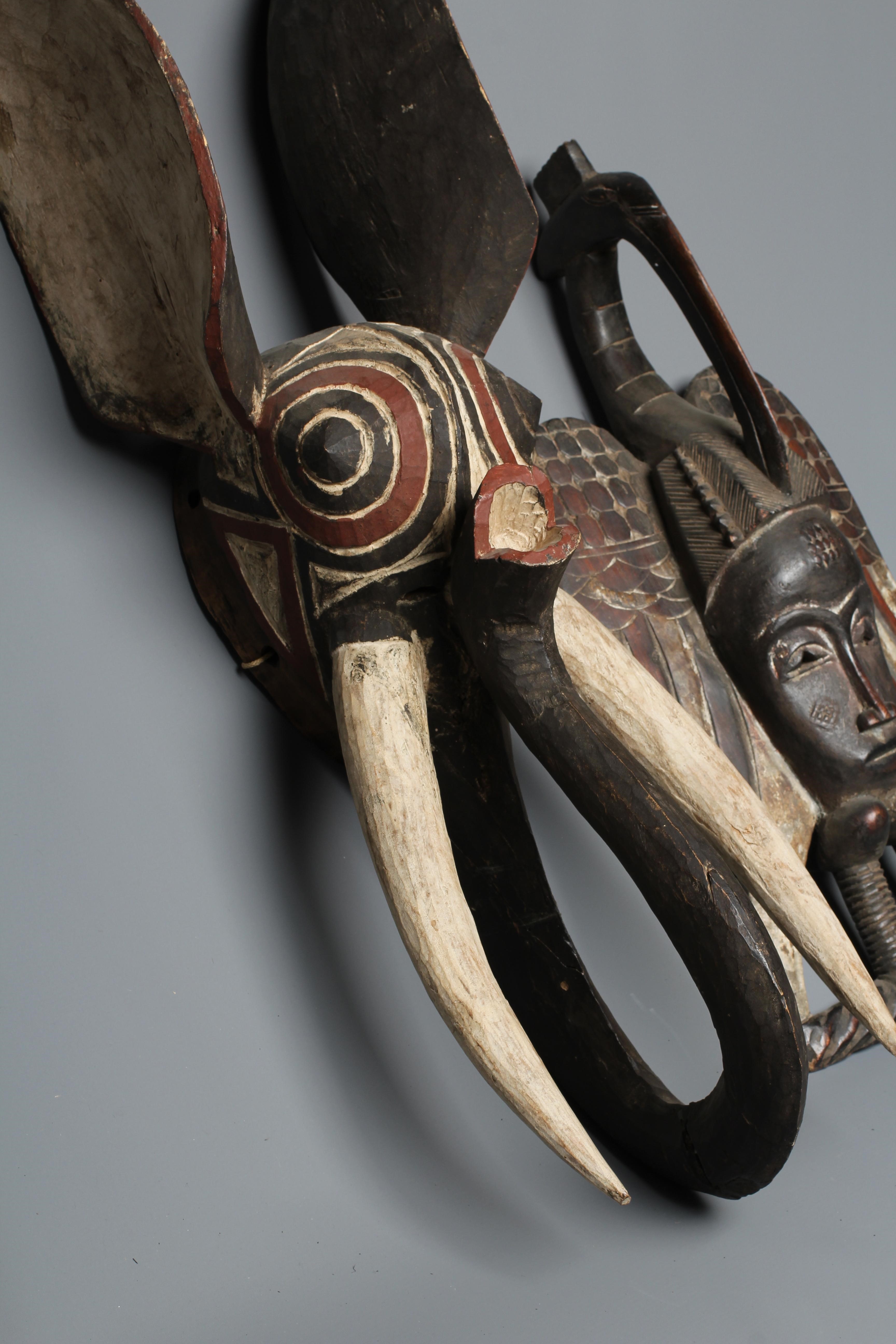 A CENTRAL AFRICAN CARVED WOOD ELEPHANT MASK, hand painted with shaped curved trunk, alert ears and Image