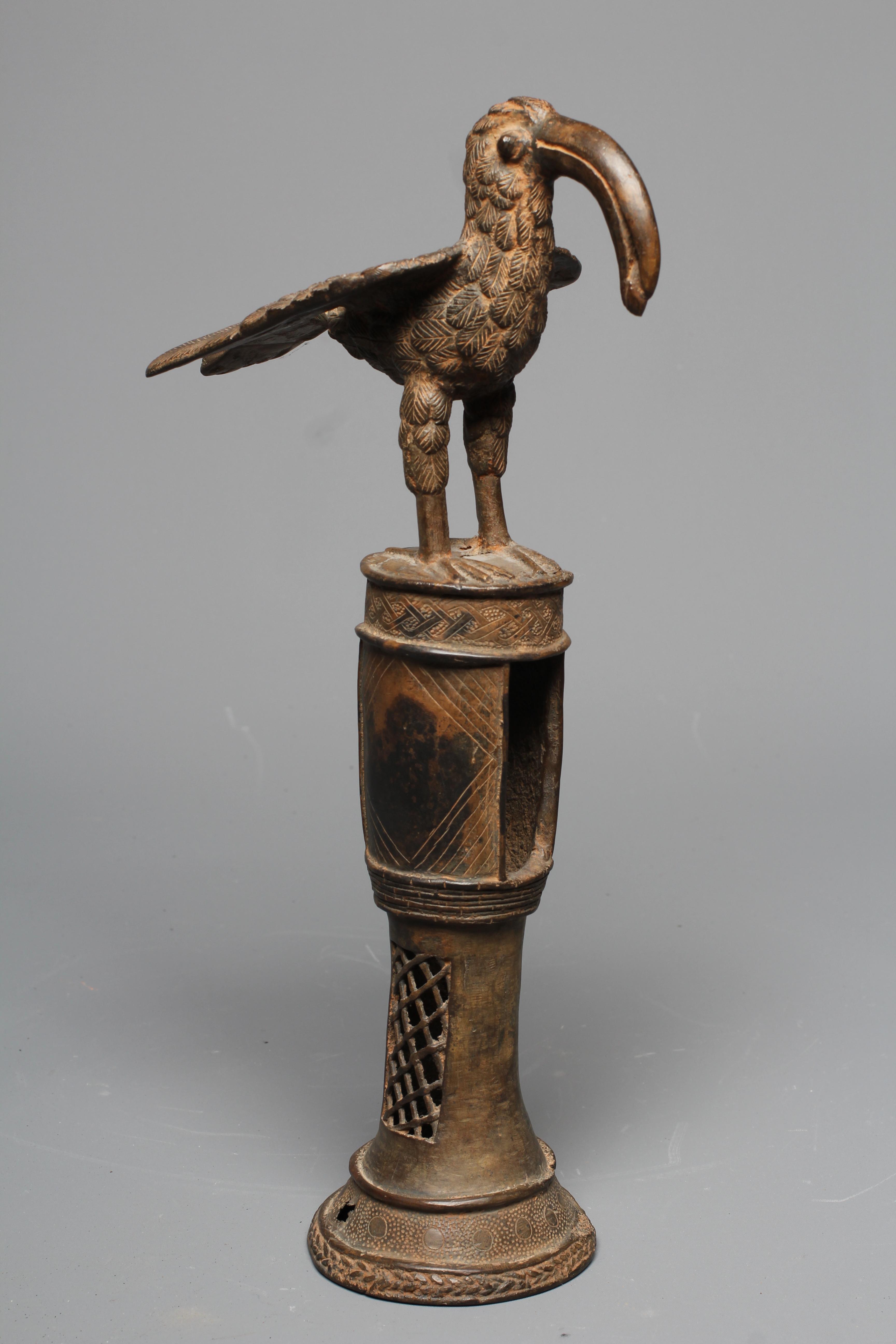 A BENIN BRASS IDIOPHONE, brass, iron, with pierced cylindrical shaft, surmounted a long-billed bird Image