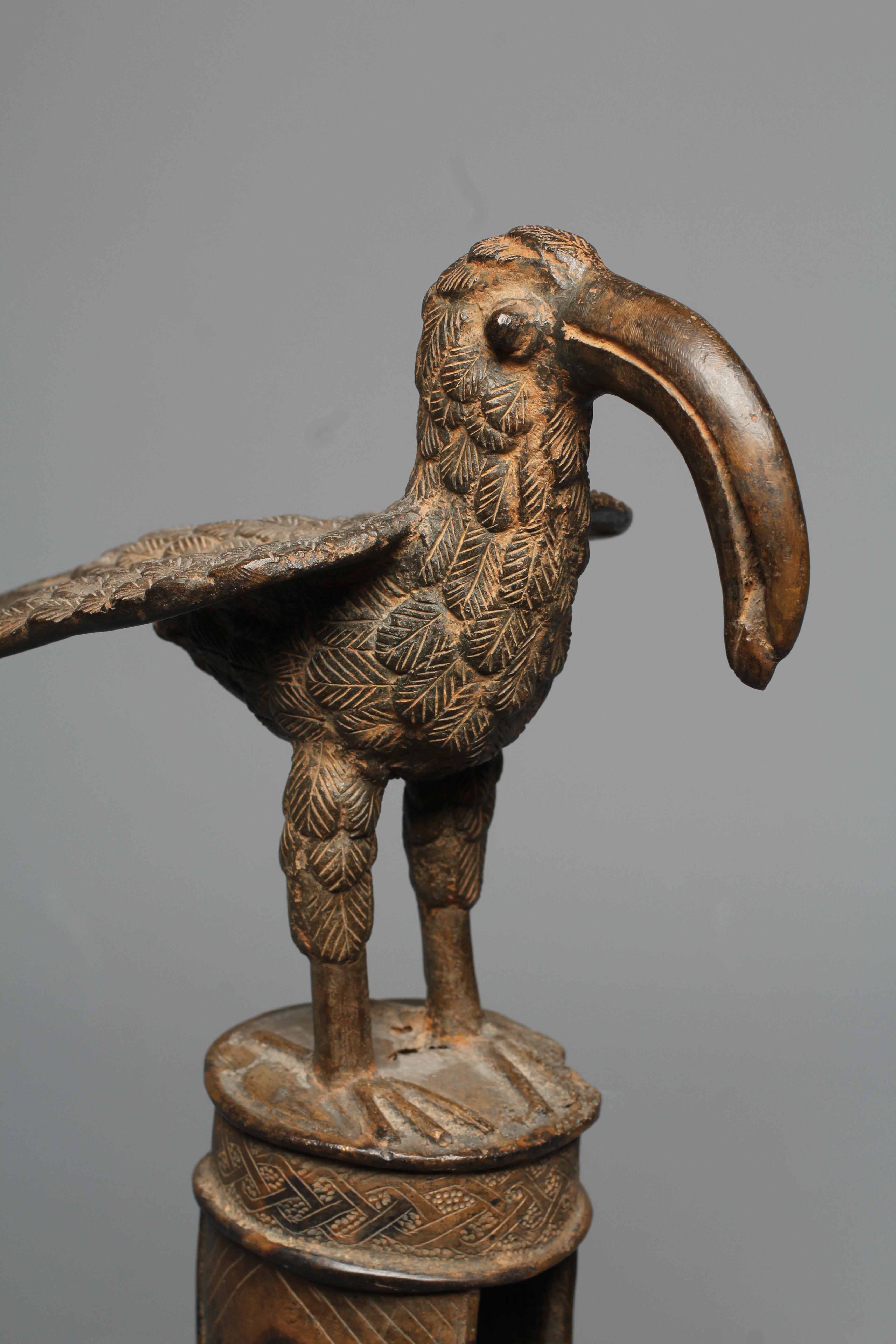 A BENIN BRASS IDIOPHONE, brass, iron, with pierced cylindrical shaft, surmounted a long-billed bird Image