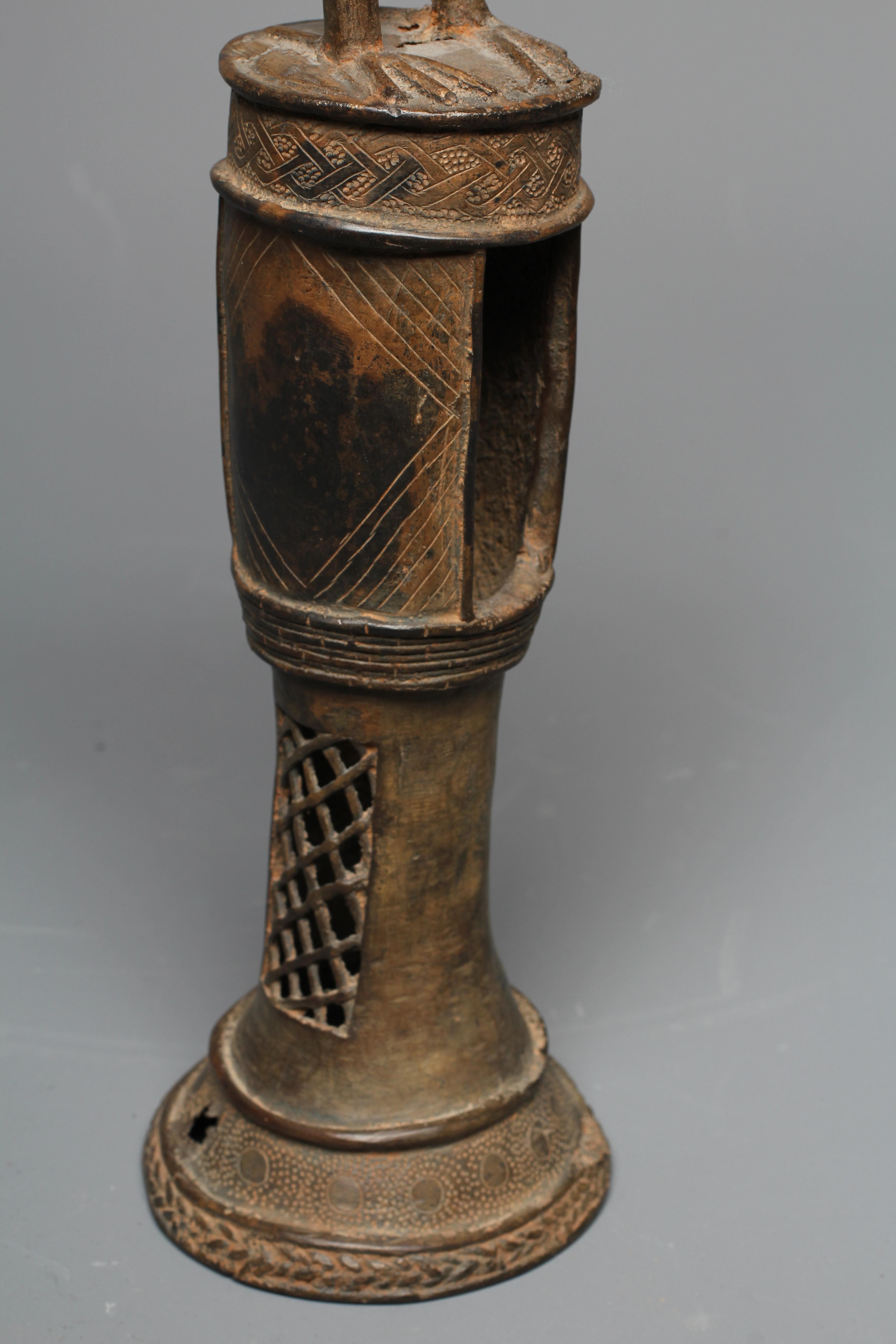A BENIN BRASS IDIOPHONE, brass, iron, with pierced cylindrical shaft, surmounted a long-billed bird Image