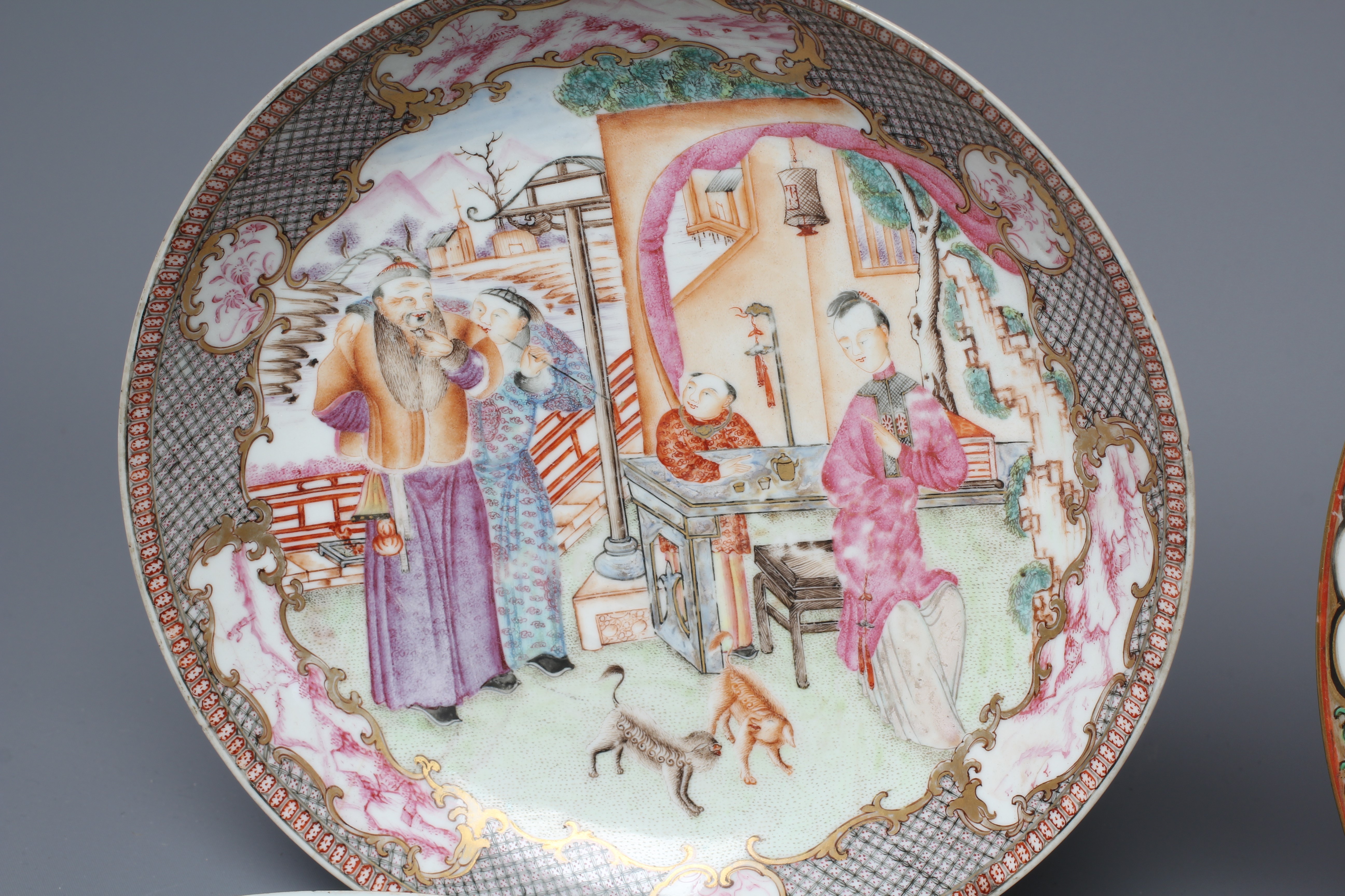 FOUR CHINESE FAMILLE ROSE PORCELAIN PLATES comprising a saucer dish with figures and dogs on a Image