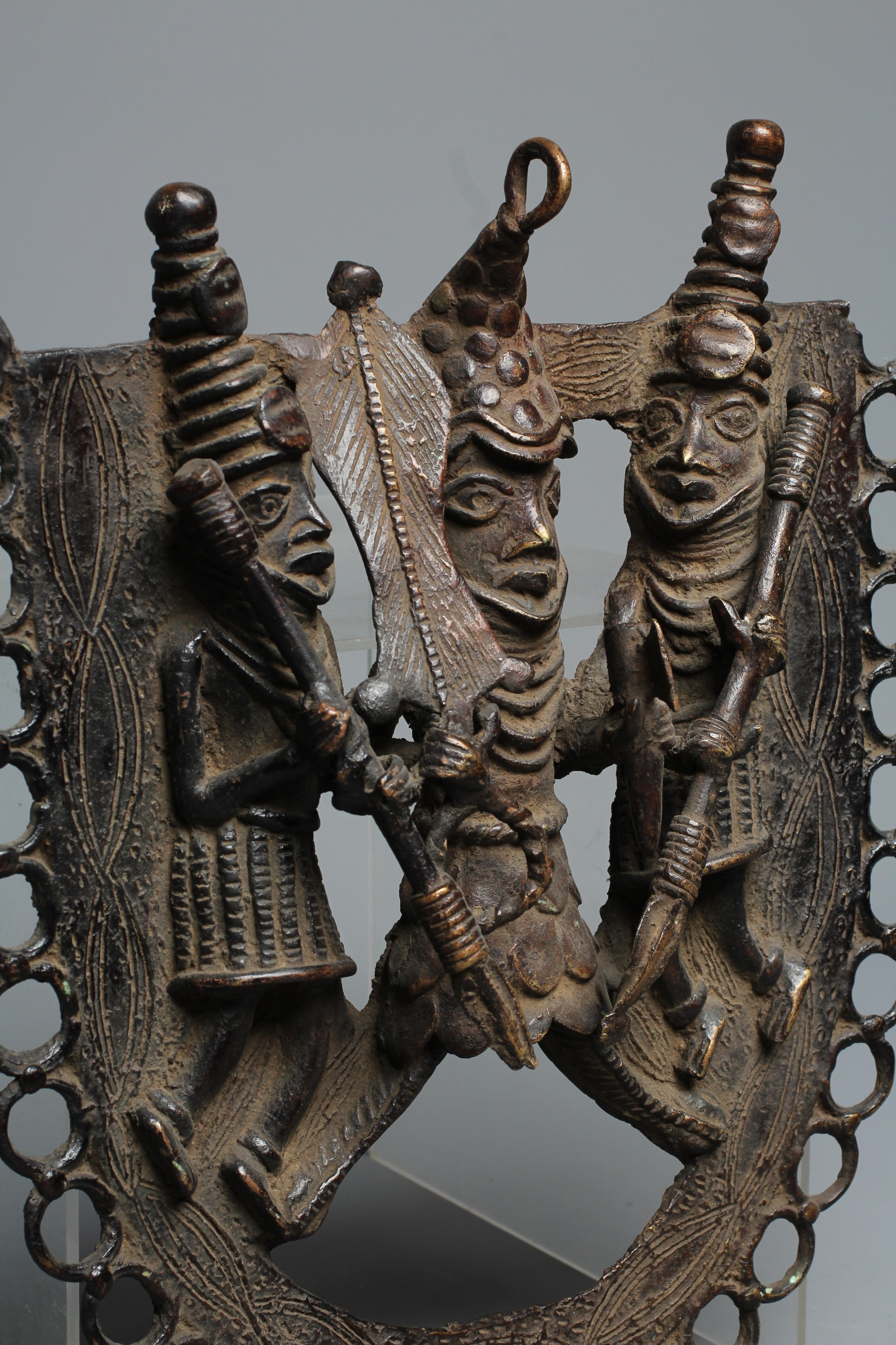 A BENIN PATINATED BRONZE PLAQUE worked in relief with three warriors within a stylised ringlet Image