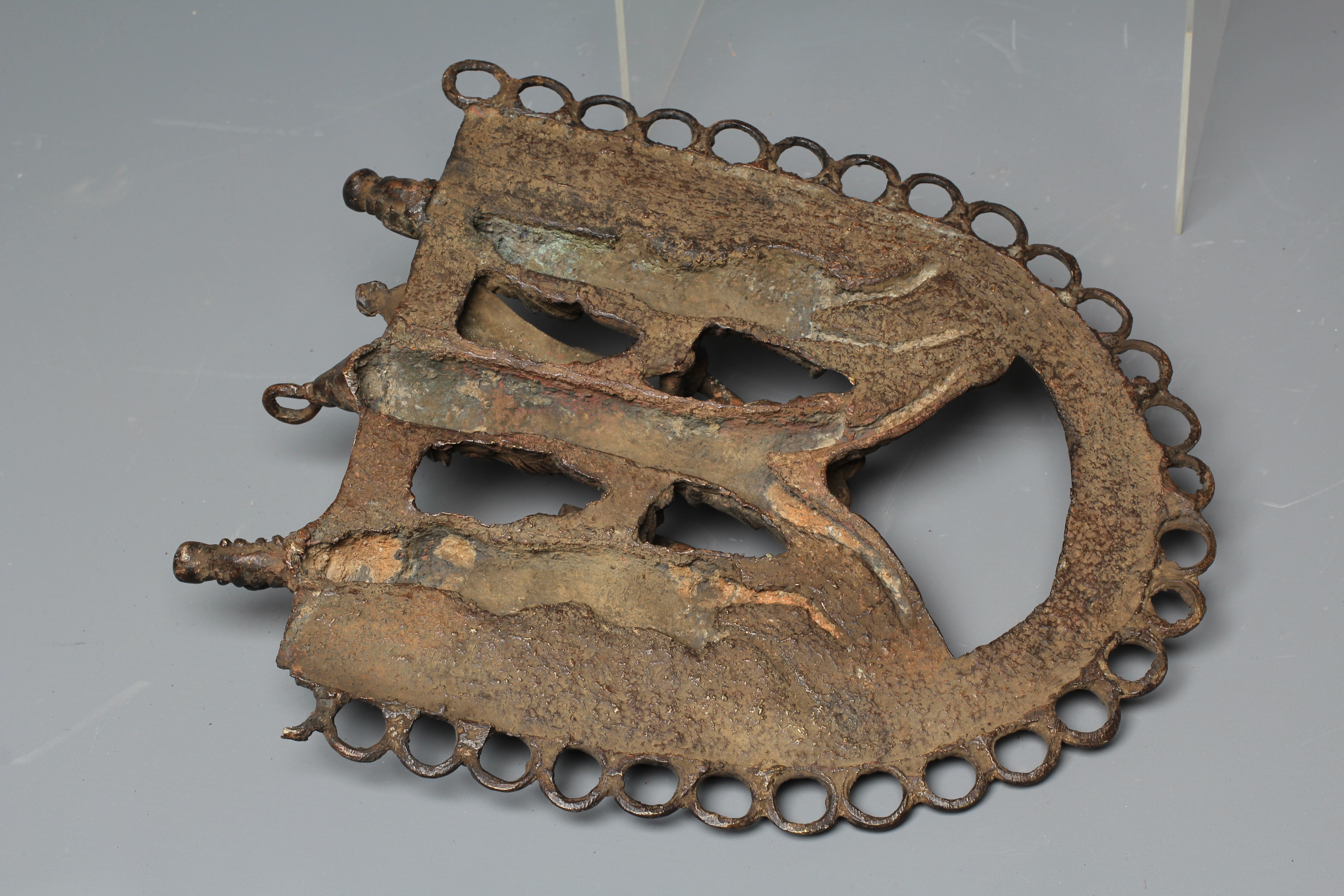 A BENIN PATINATED BRONZE PLAQUE worked in relief with three warriors within a stylised ringlet Image
