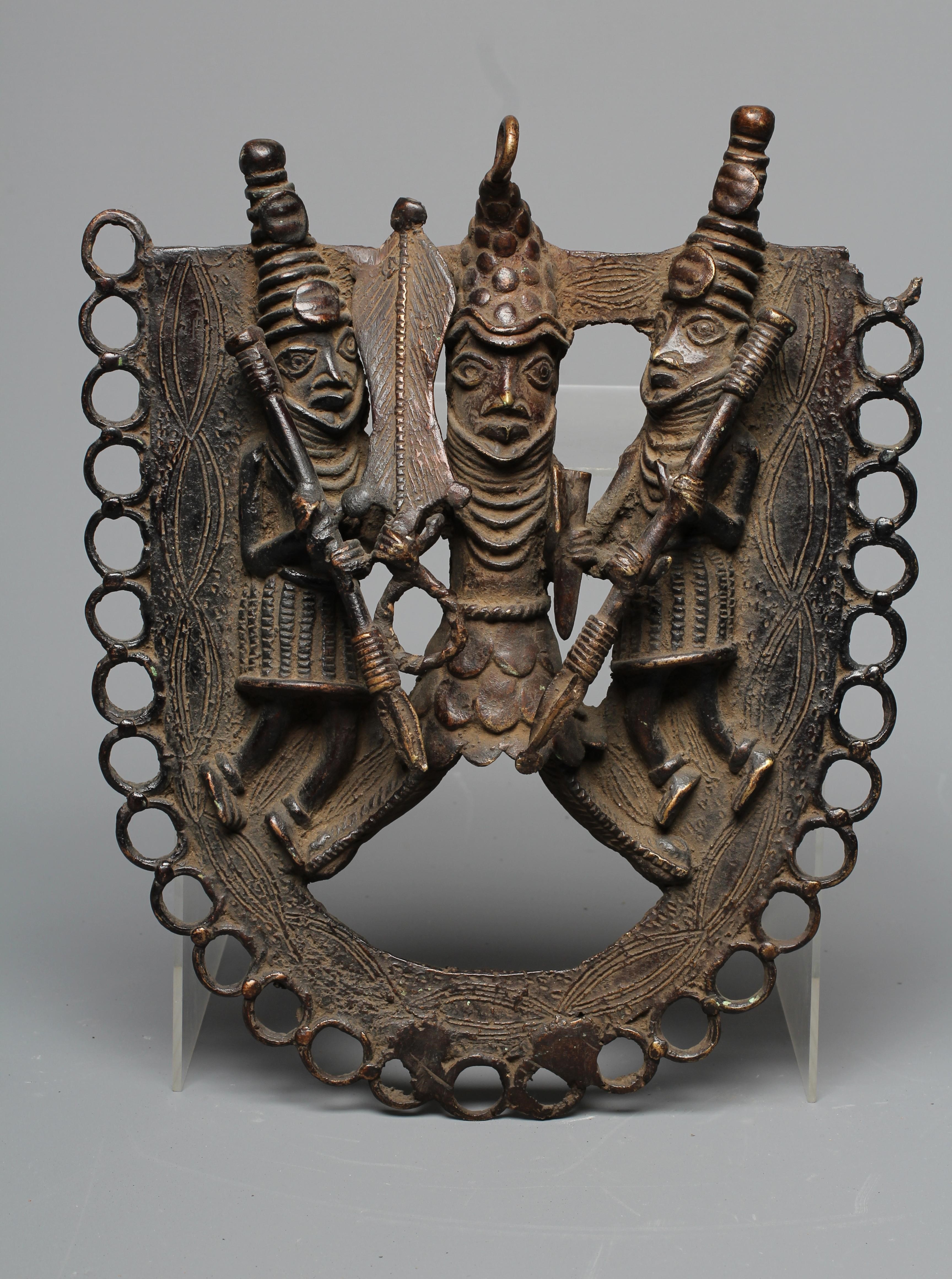 A BENIN PATINATED BRONZE PLAQUE worked in relief with three warriors within a stylised ringlet Image