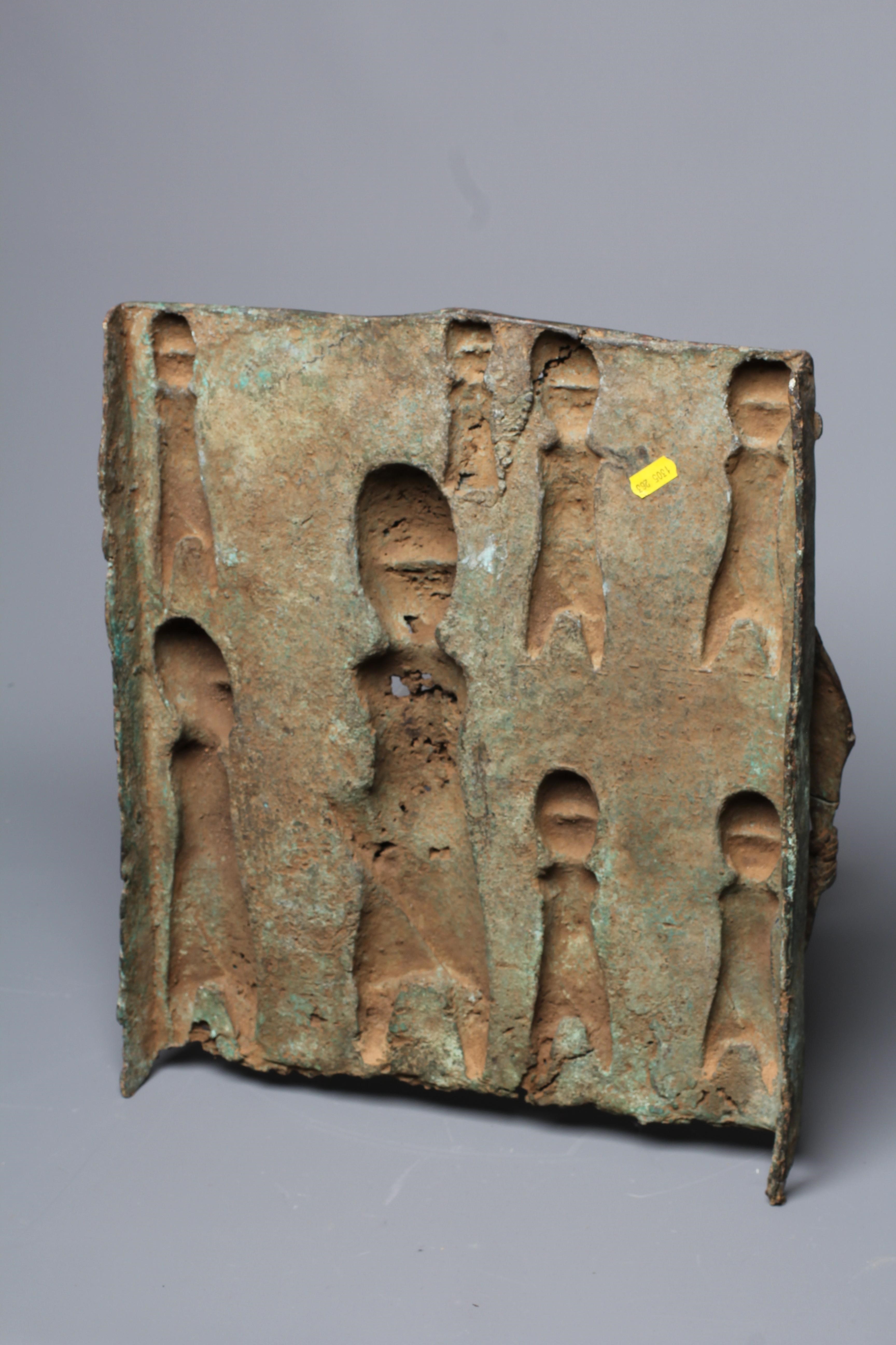 A BENIN BRONZE PLAQUE worked in relief depicting Obas butchers carrying a sacrificial cow, 18 1/2" Image