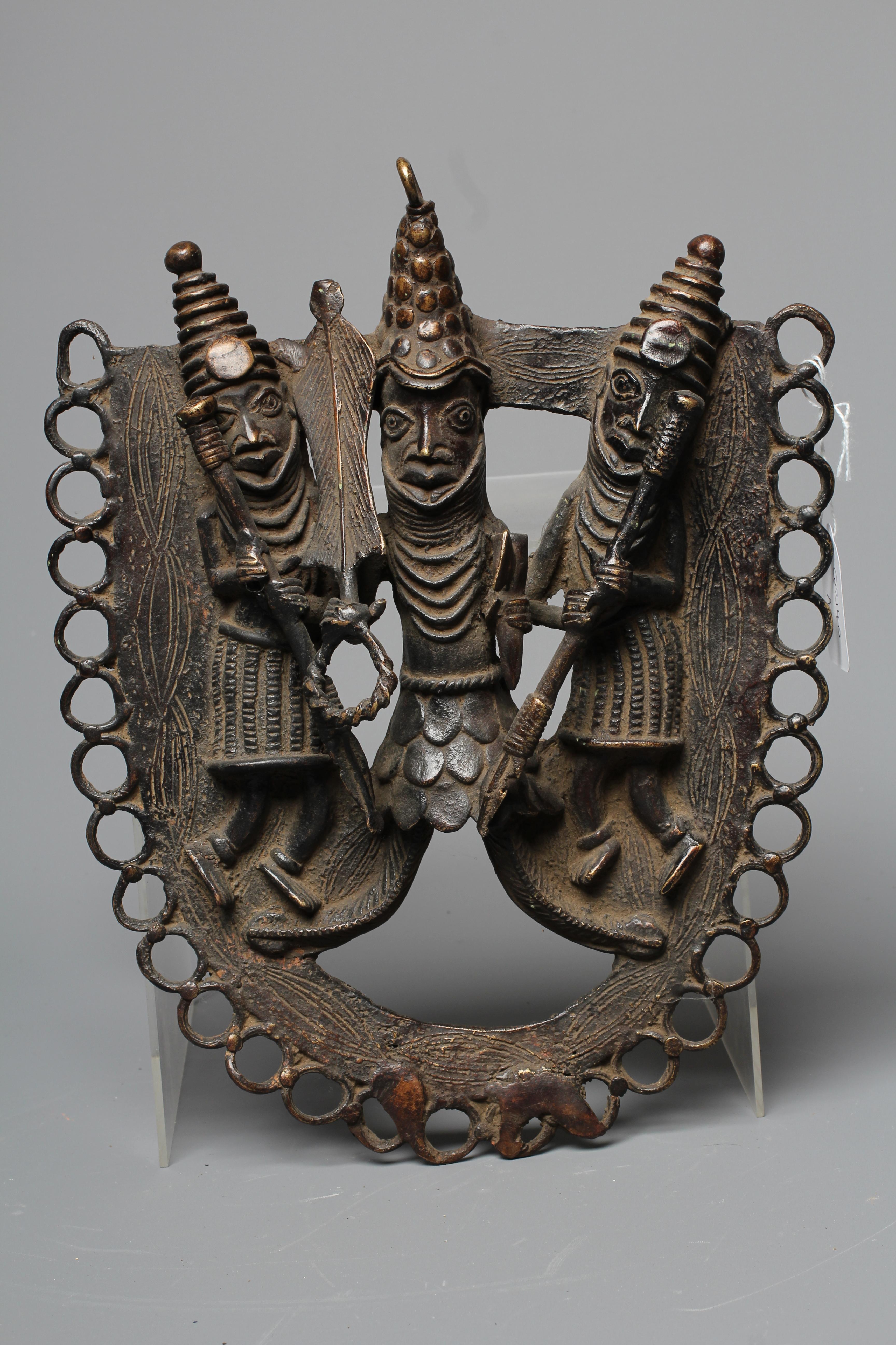 A BENIN PATINATED BRONZE PLAQUE worked in relief with three warrior figures within a stylised Image