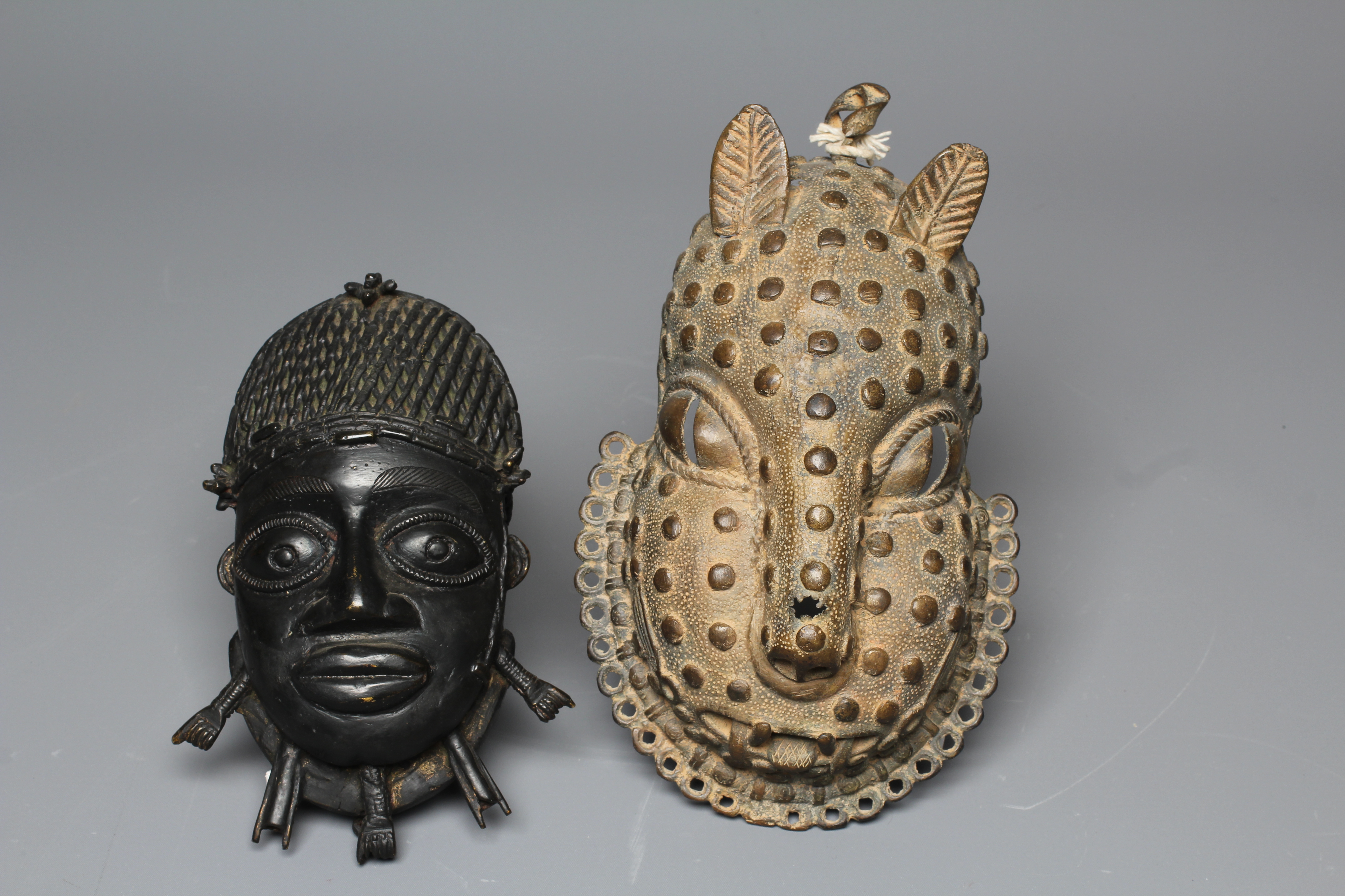 A BENIN CAST BRASS PENDANT MASK with tooled decoration, 8" high, together with a second Benin brass Image