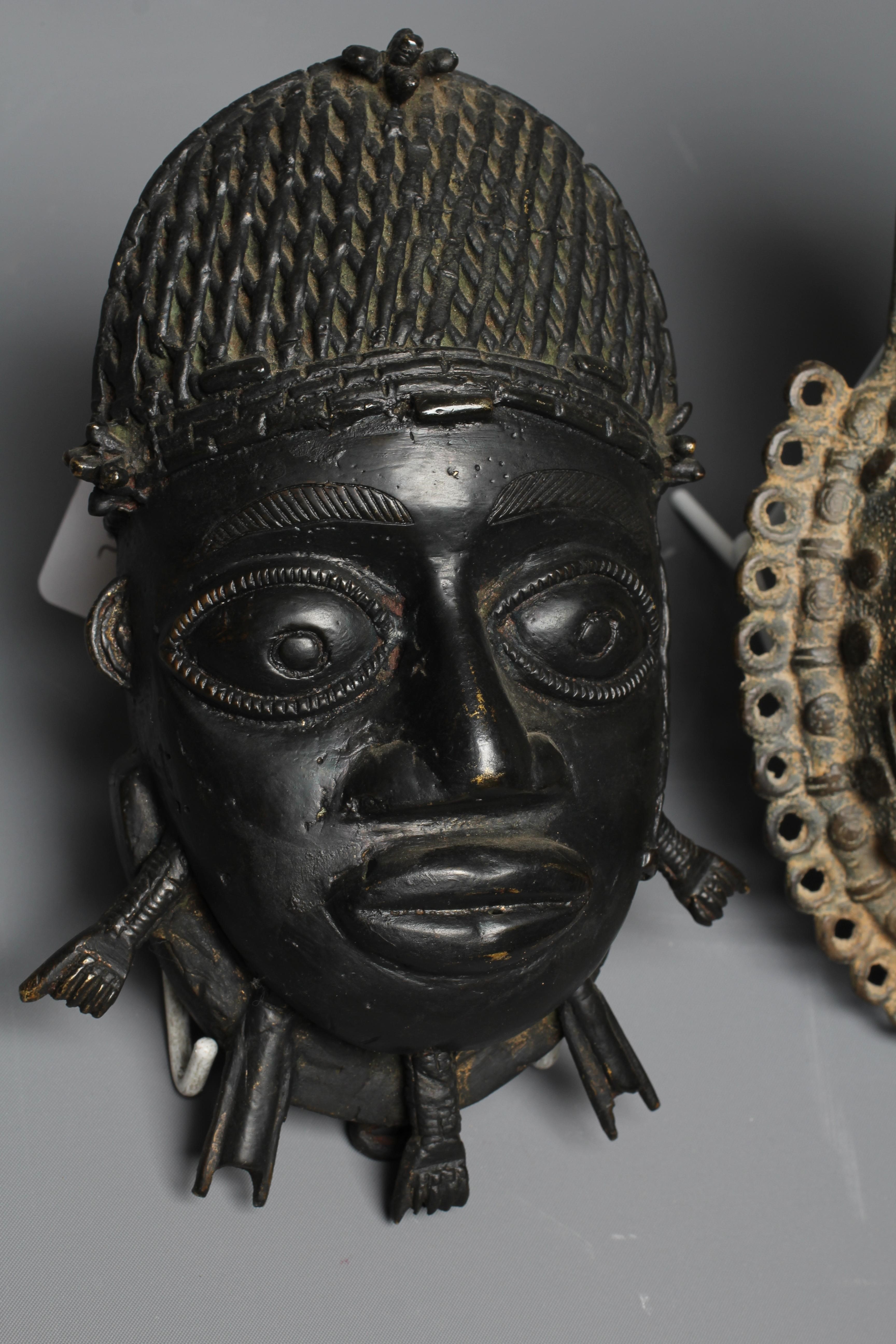 A BENIN CAST BRASS PENDANT MASK with tooled decoration, 8" high, together with a second Benin brass Image