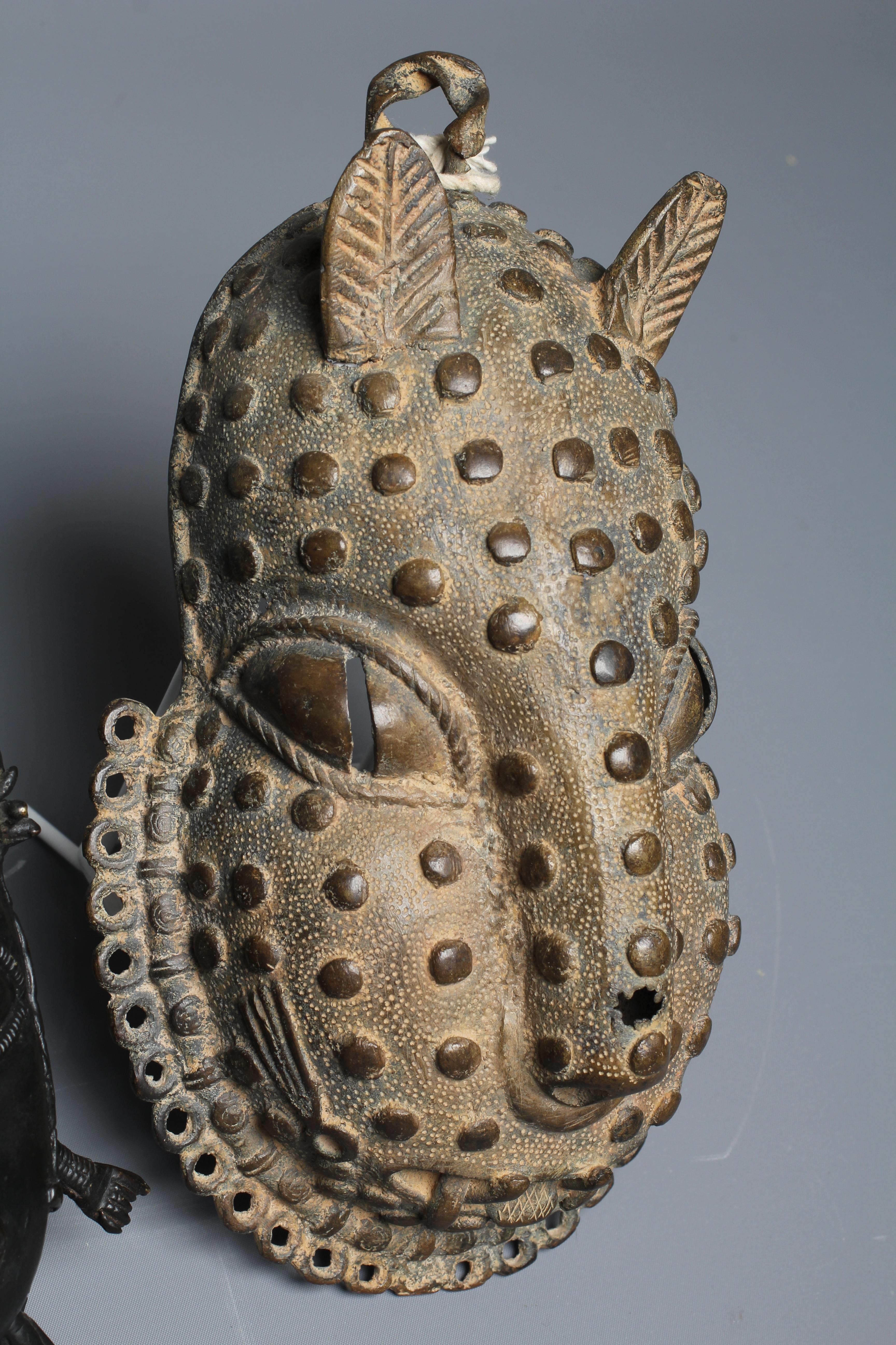 A BENIN CAST BRASS PENDANT MASK with tooled decoration, 8" high, together with a second Benin brass Image