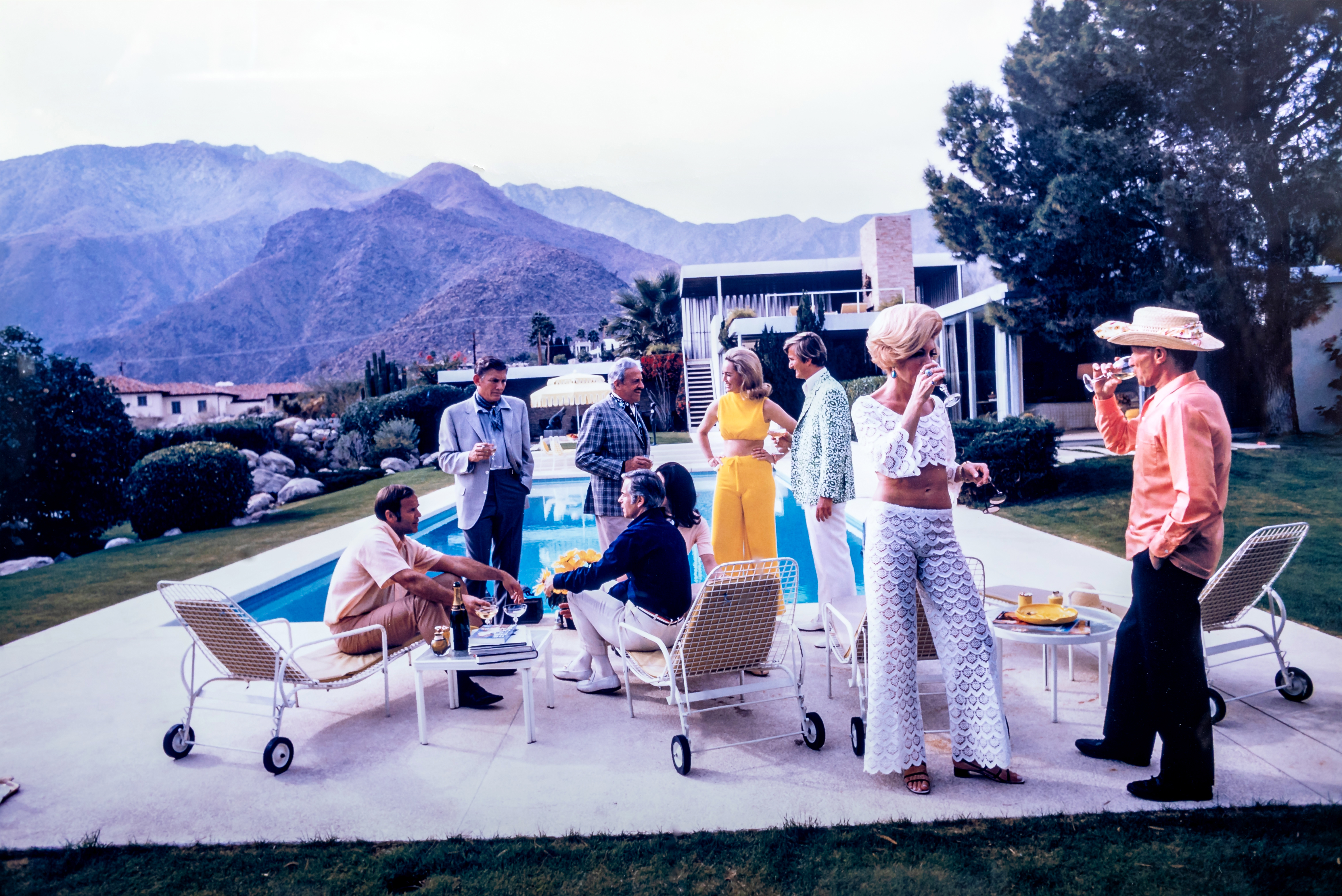 AFTER SLIM AARONS (1916-2000) Desert House Party, photographic print, 26" x 39" (SH), framed and Image