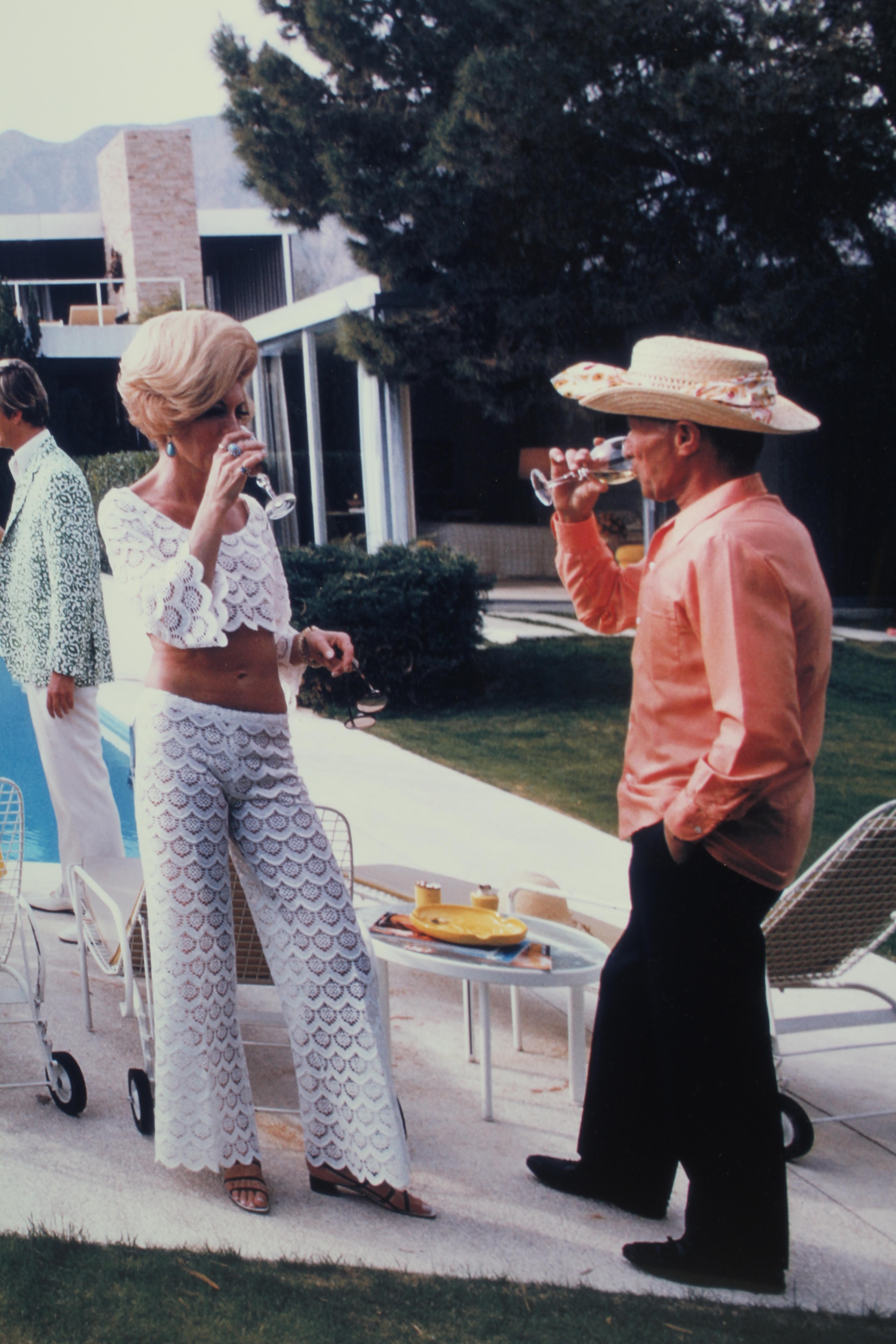 AFTER SLIM AARONS (1916-2000) Desert House Party, photographic print, 26" x 39" (SH), framed and Image