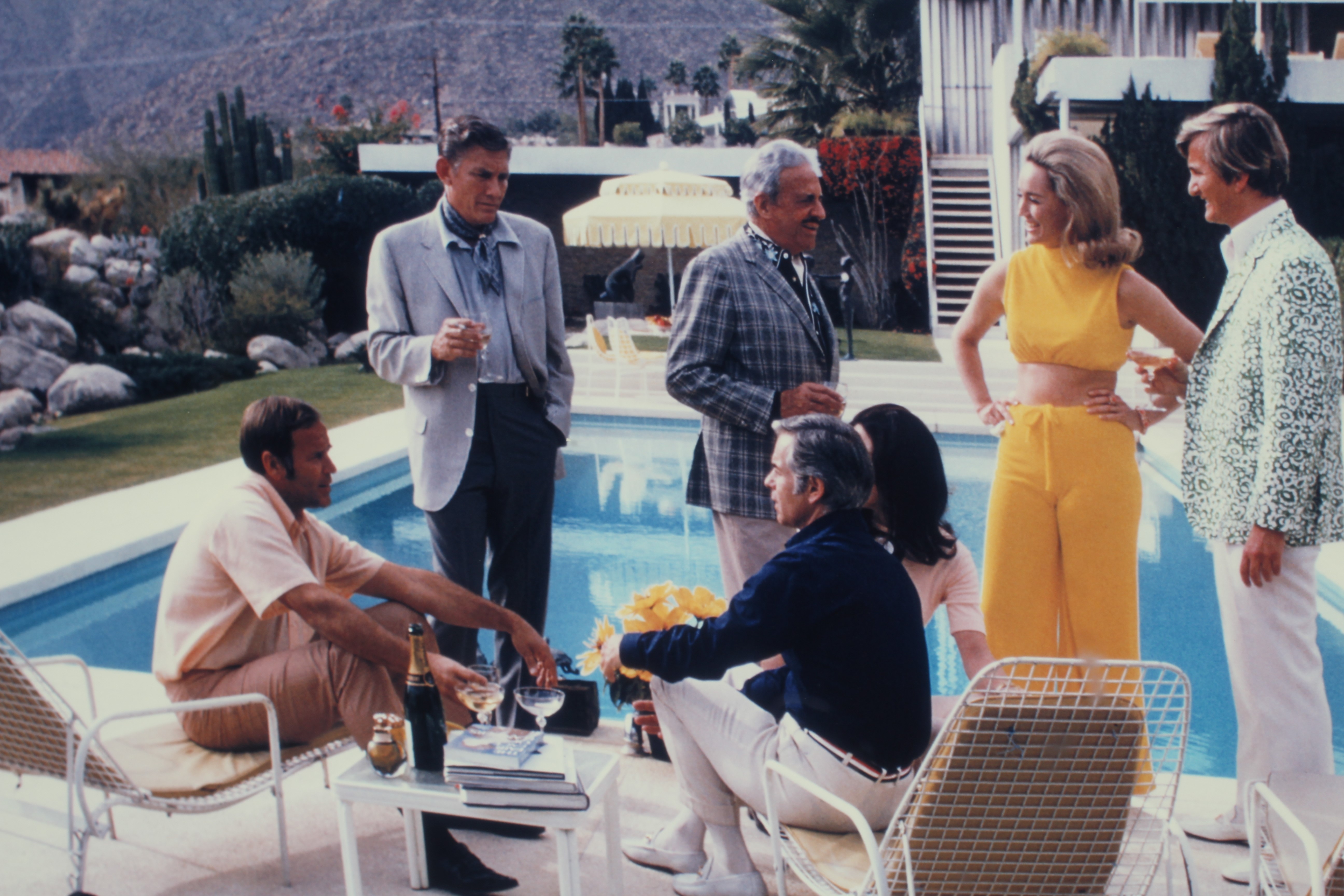 AFTER SLIM AARONS (1916-2000) Desert House Party, photographic print, 26" x 39" (SH), framed and Image