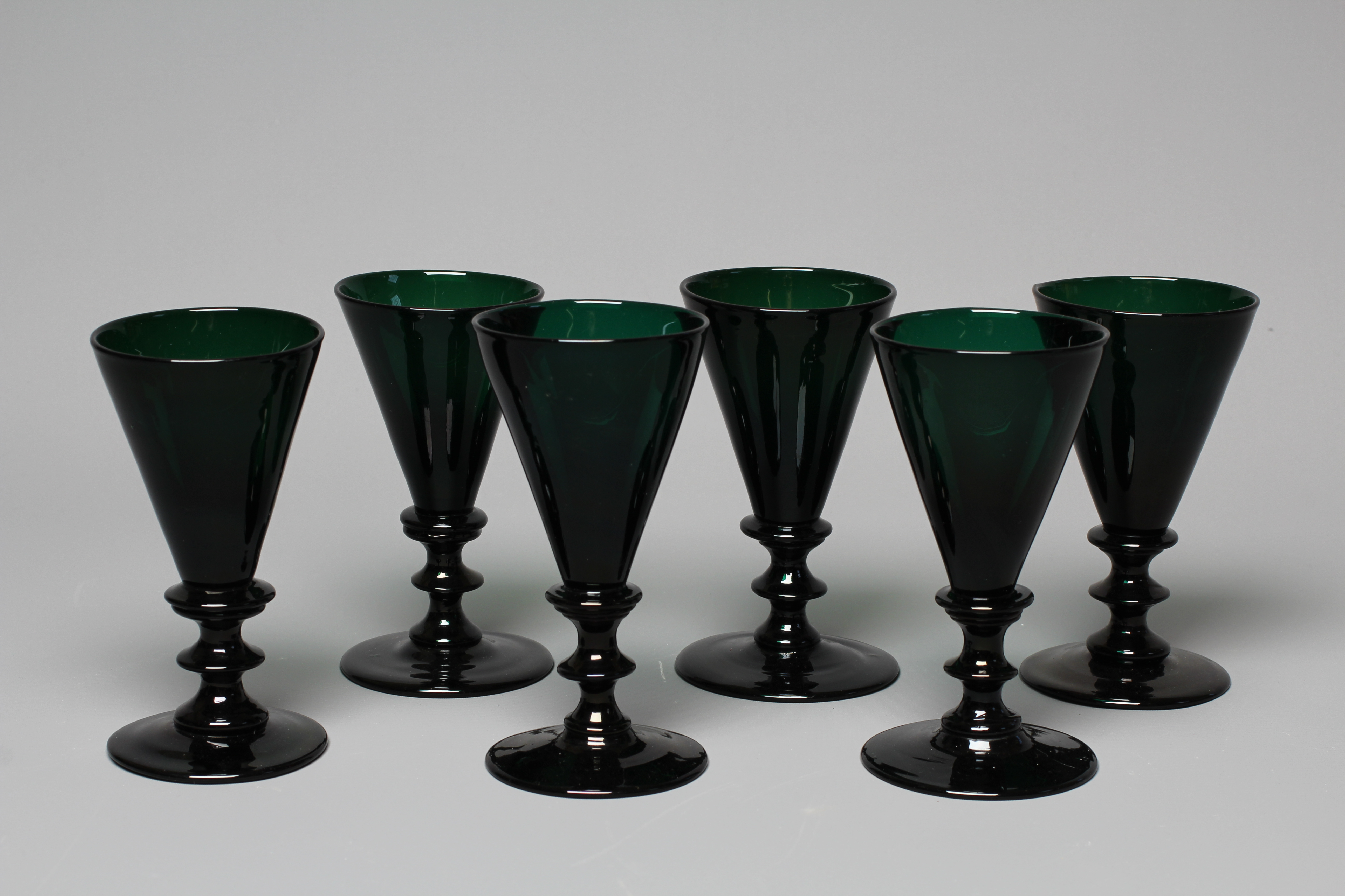 A SET OF SIX BRISTOL GREEN GLASS FLUTES, early 19th century, the conical bowls issuing from double Image