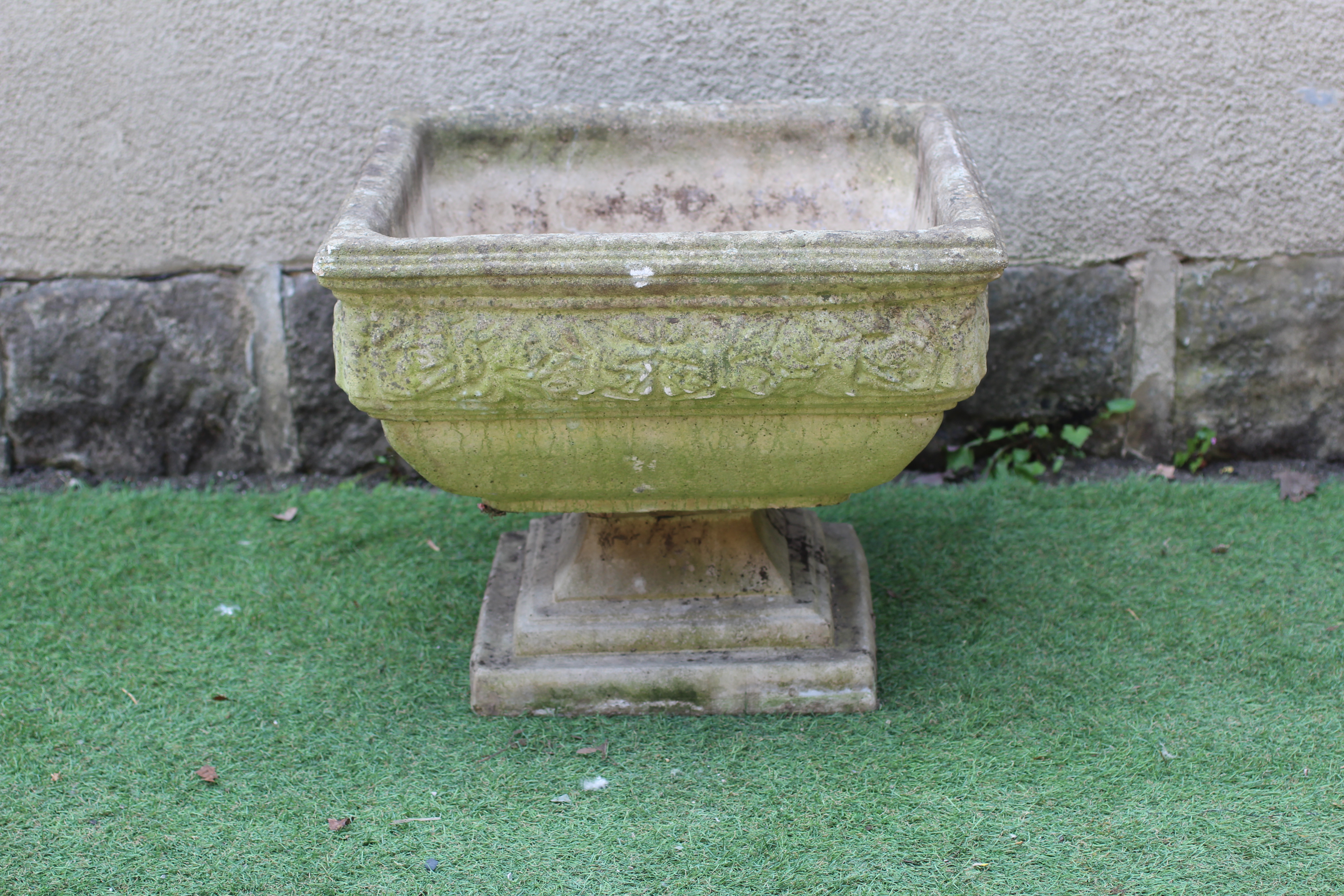 A CAST STONE PLANTER, modern, of shallow square form with leaf moulded cushion body, raised on Image