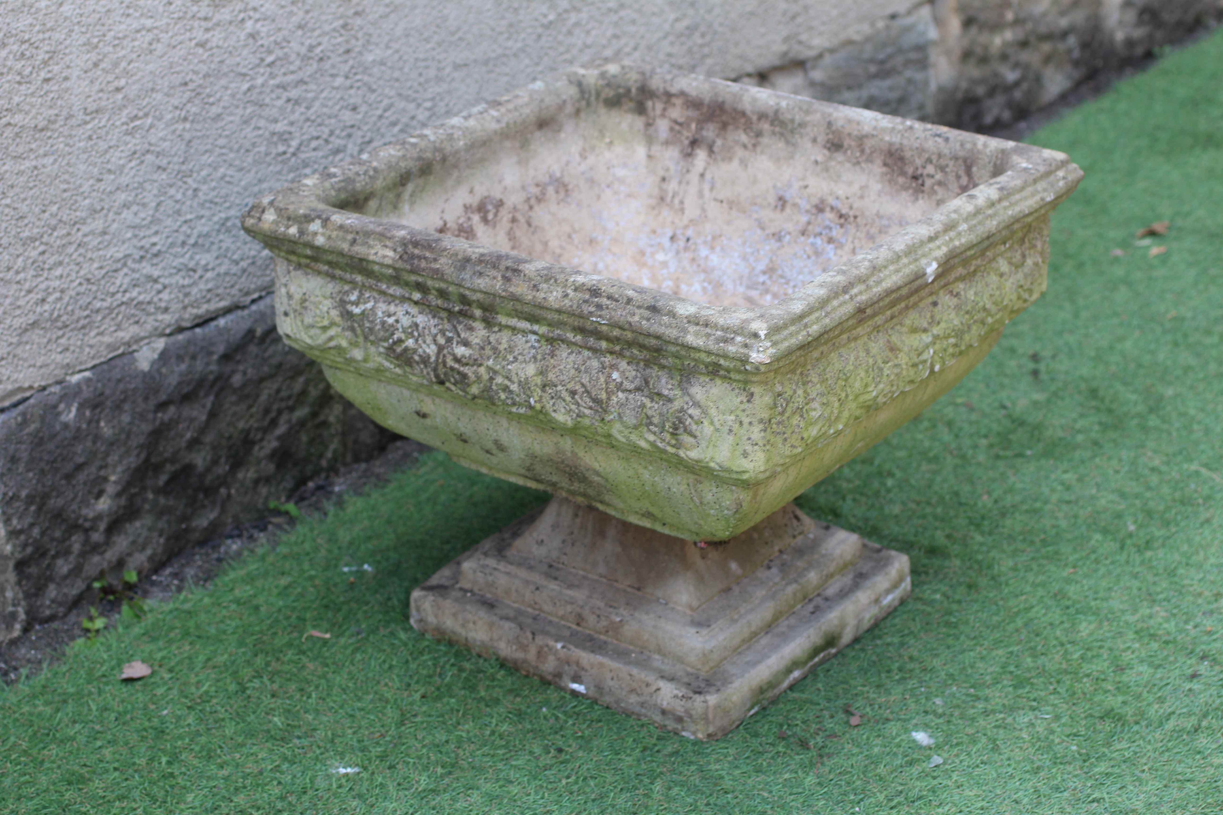 A CAST STONE PLANTER, modern, of shallow square form with leaf moulded cushion body, raised on Image
