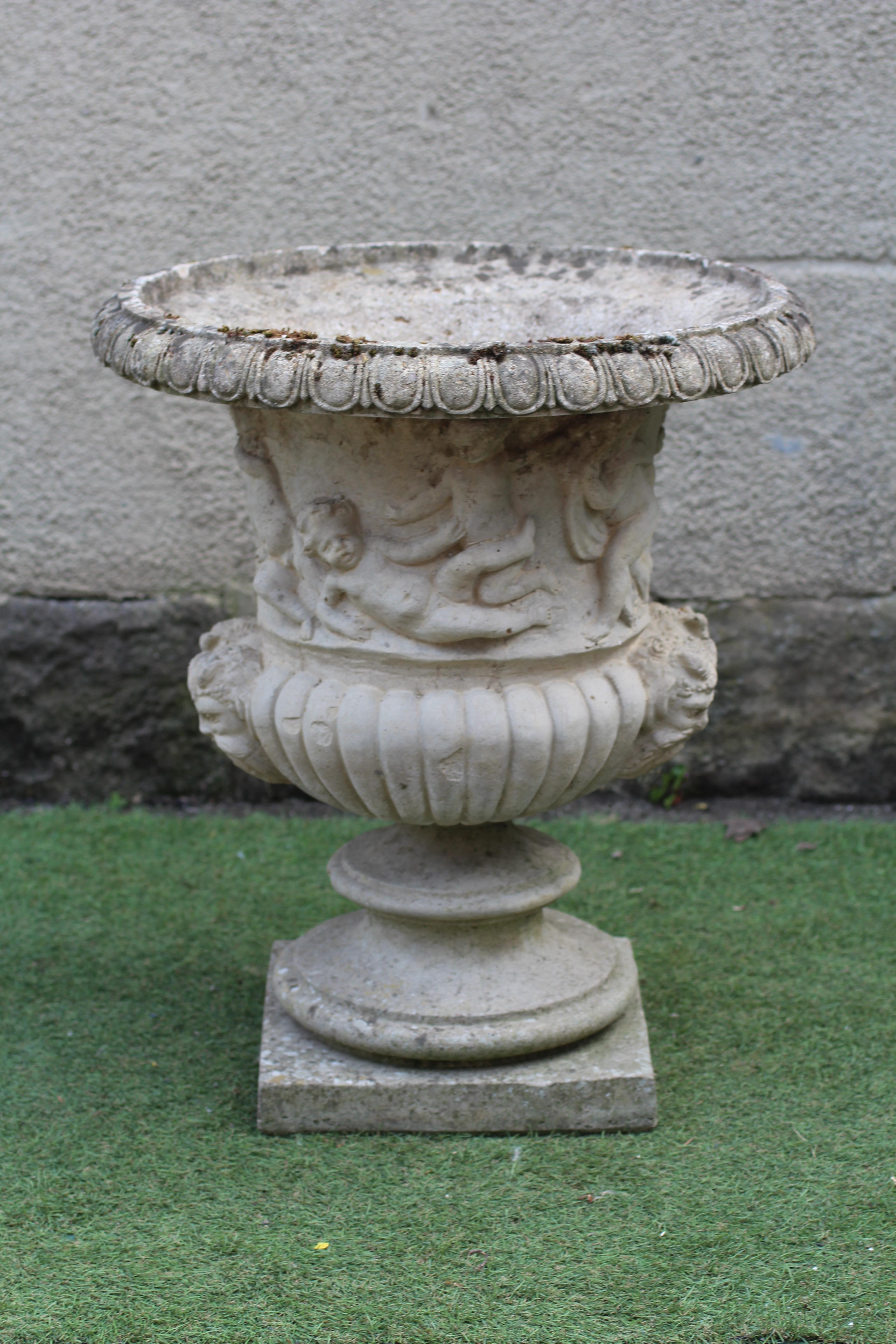 A CAST STONE URN of half fluted campana form with egg and dart moulded rim Image