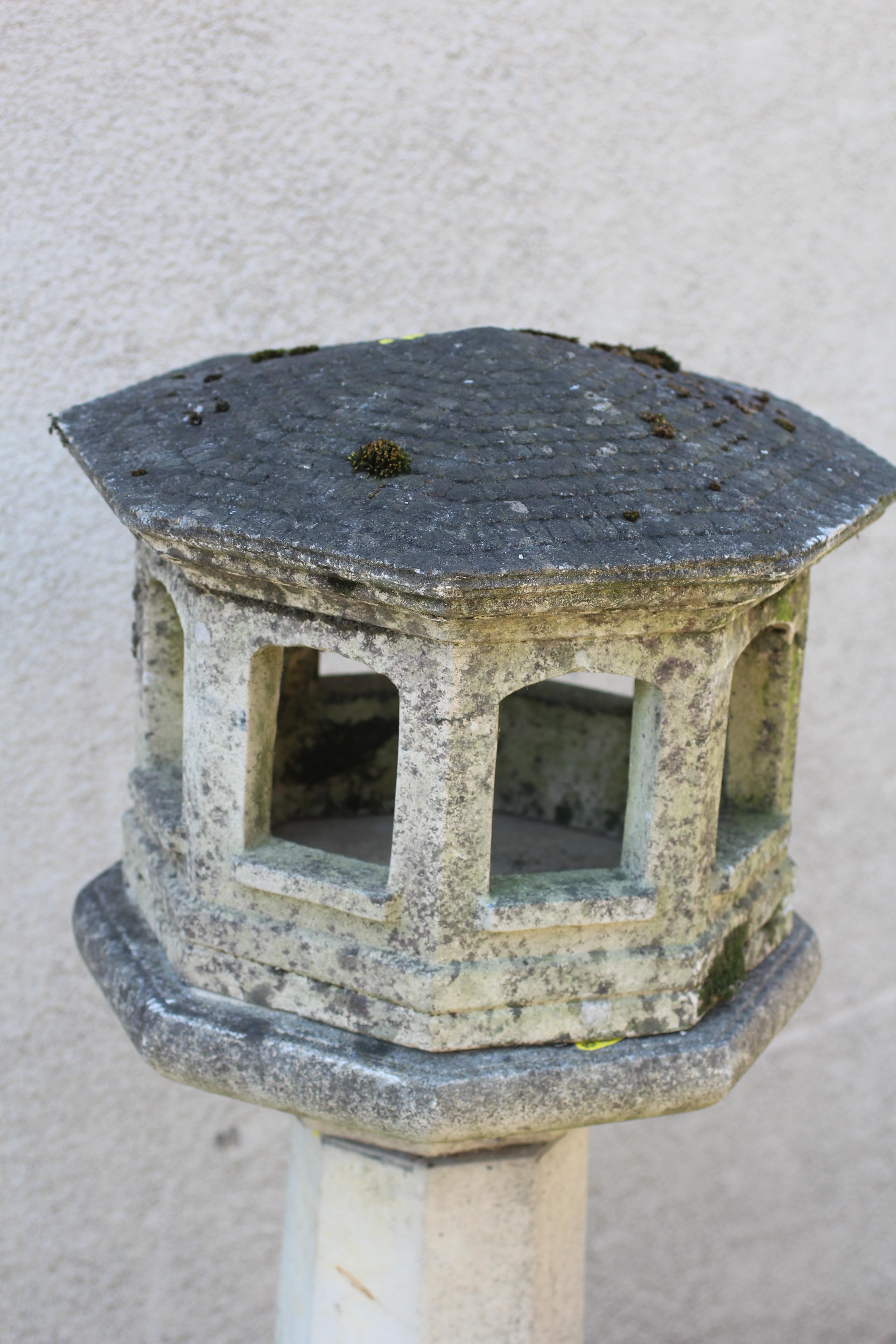 A CAST STONE OCTAGONAL LANTERN, the open sided hood with domed roof, raised on square tapering stem Image