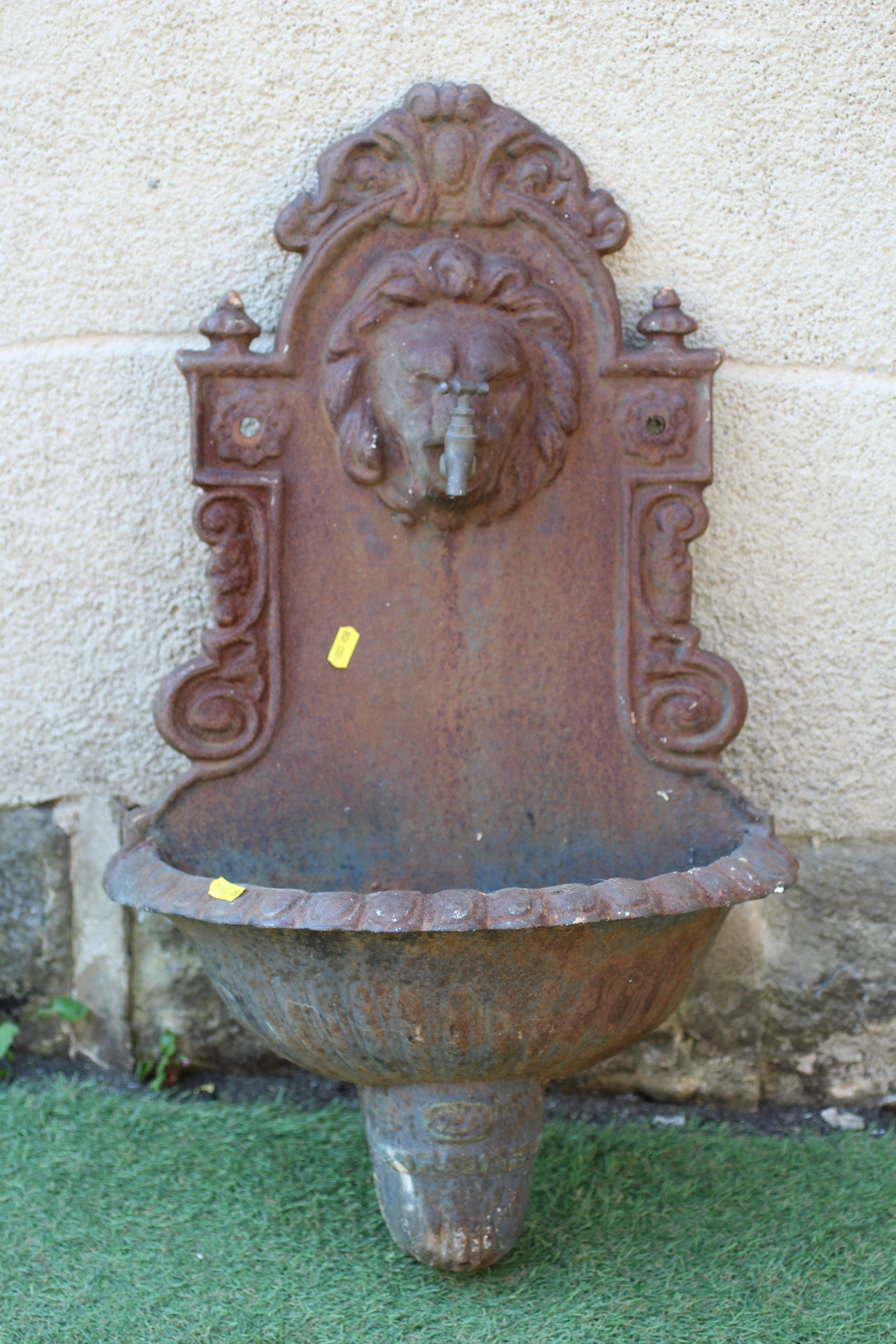 A SMALL CAST IRON WALL FOUNTAIN, the arched scroll edged back with lion head faucet, the bowl with Image